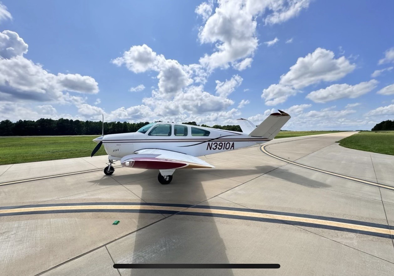 Small white private jet with registration N3910A parked on tarmac under blue sky with clouds.