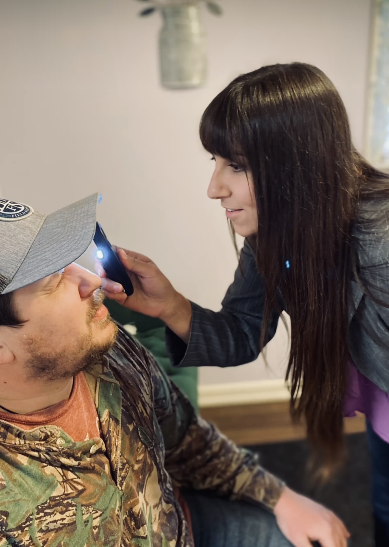 Woman taking a photo of a man with a smartphone indoors, both smiling.