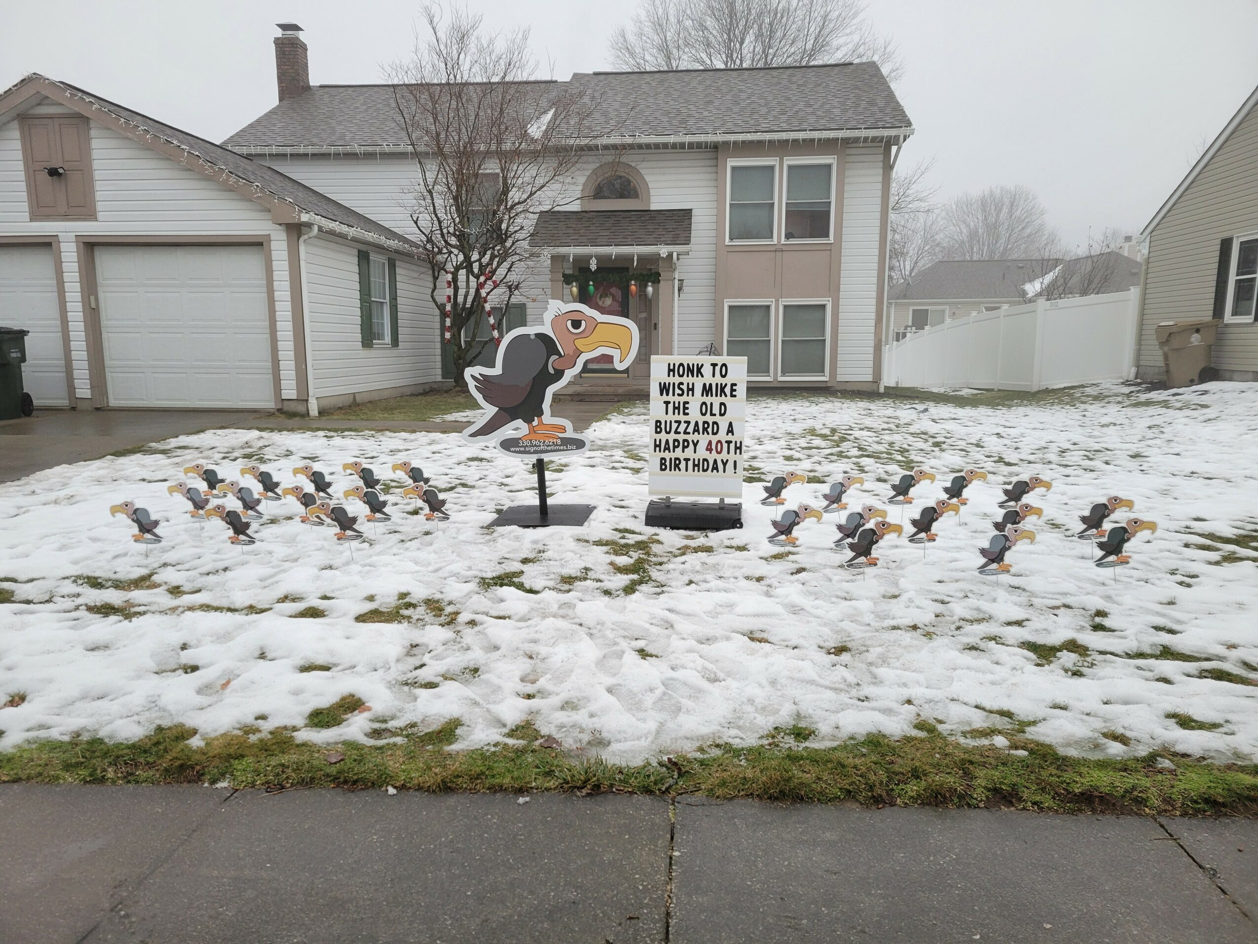 Front yard with snow, decorated with a turkey figure and a sign about turkey hunting, surrounded by small bird figures.