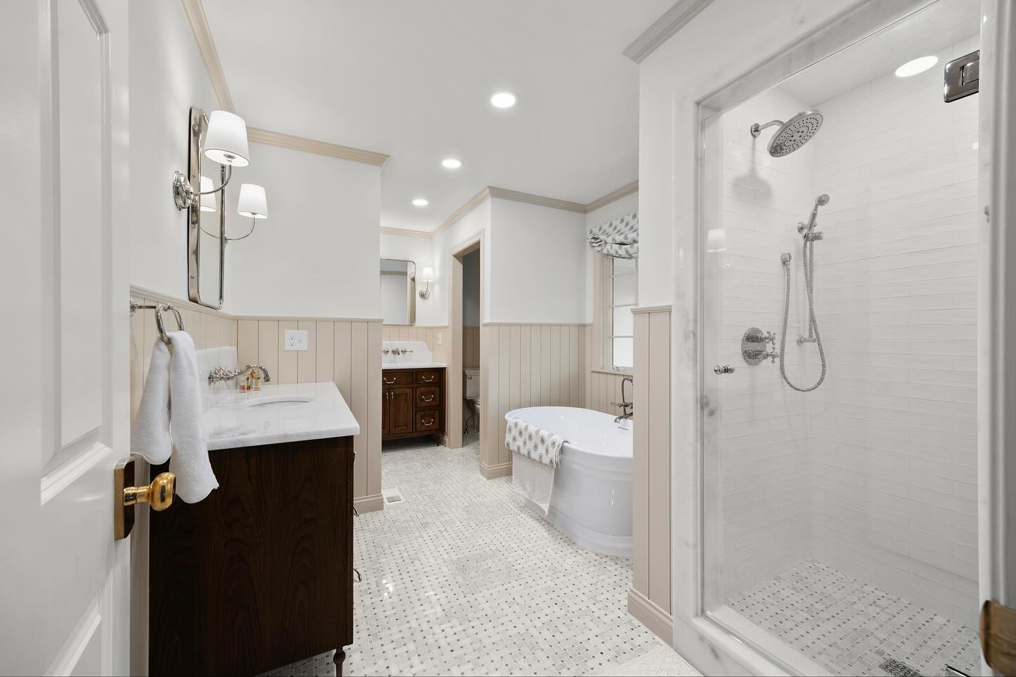 Bathroom with bathtub, shower, sink, and vanity, featuring white walls and ceiling, and a tiled floor.