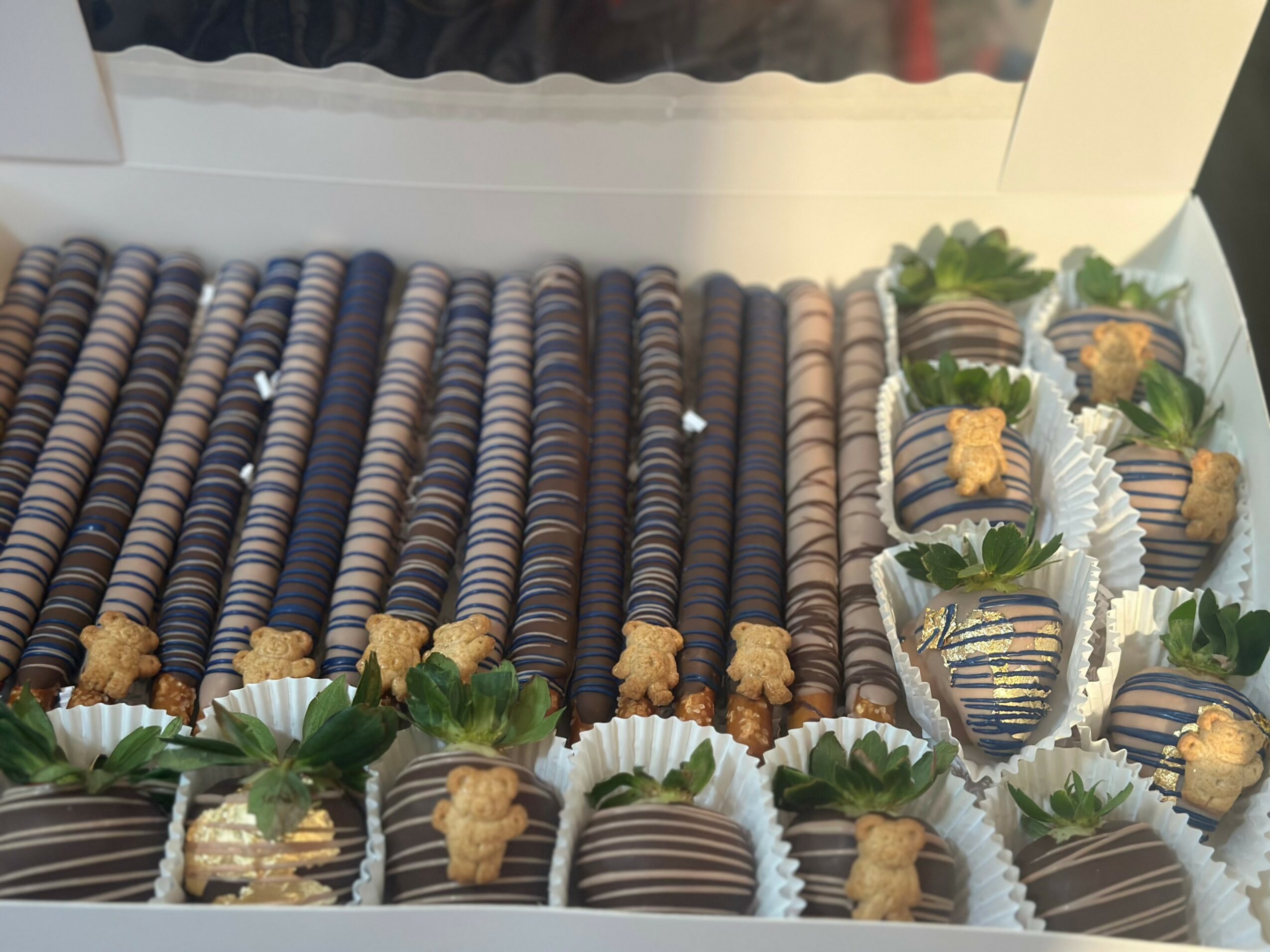 Chocolate cookies and cupcakes with green leaves and small decorations arranged on a tray, viewed from above.