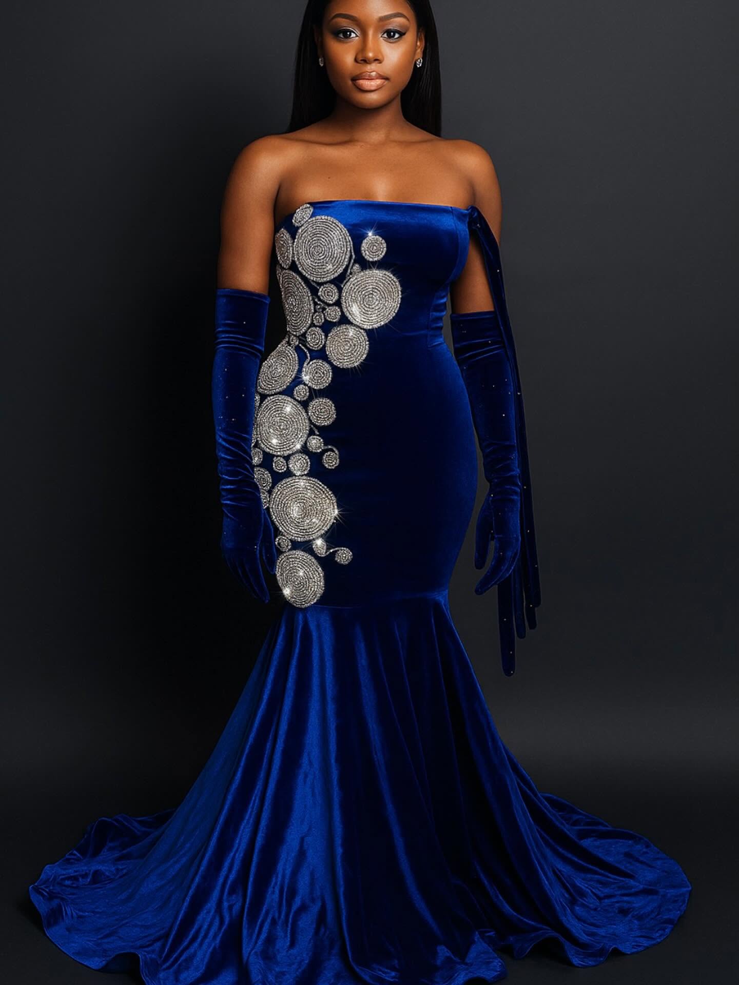 Woman in a strapless blue velvet gown with silver circular embellishments, long matching gloves, and a dark background.