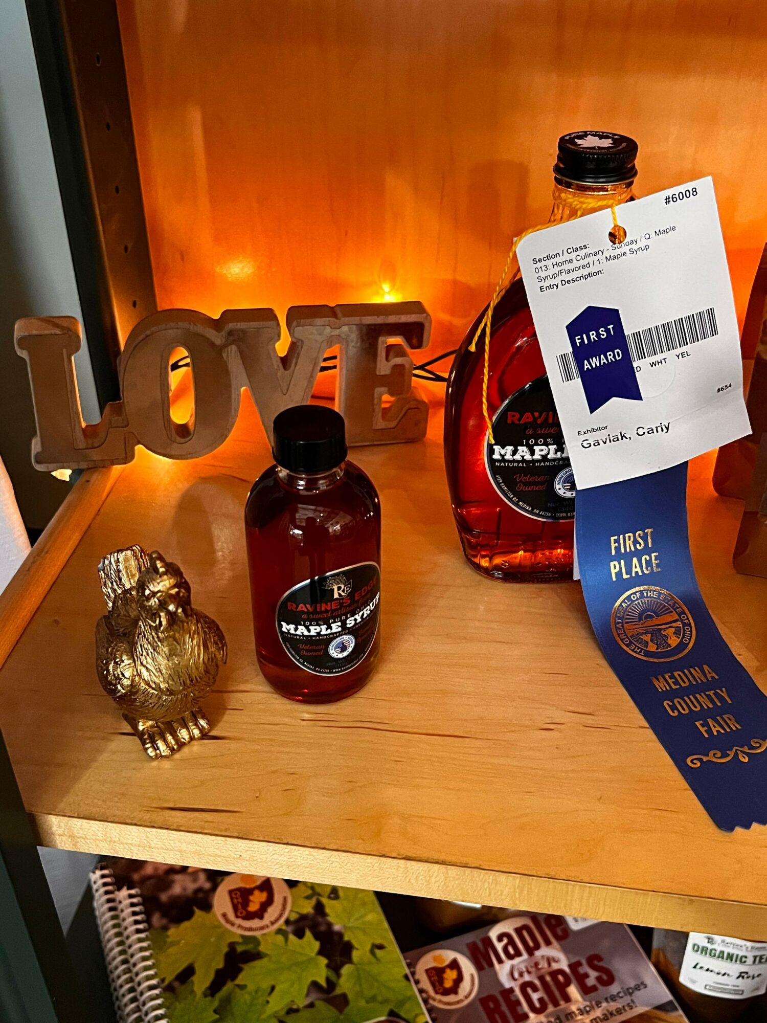 Wooden table with a bottle, a juice box, a small bottle, a decorative object, and a sign spelling 'LOVE'.