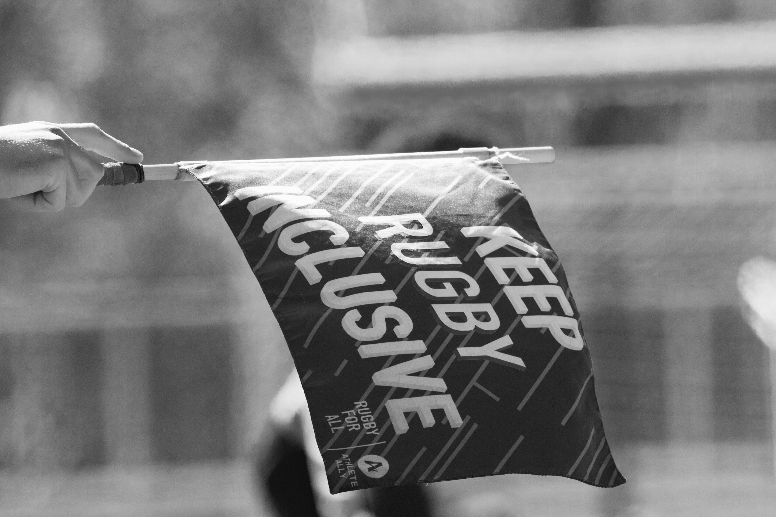 Person holding a flag with text, blurred background, black and white image.