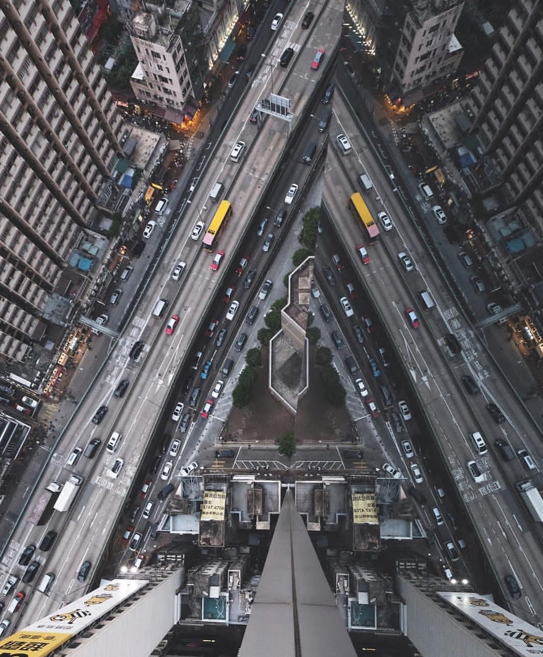 View looking down a city street from a tall building, showing multiple lanes of traffic and surrounding buildings.