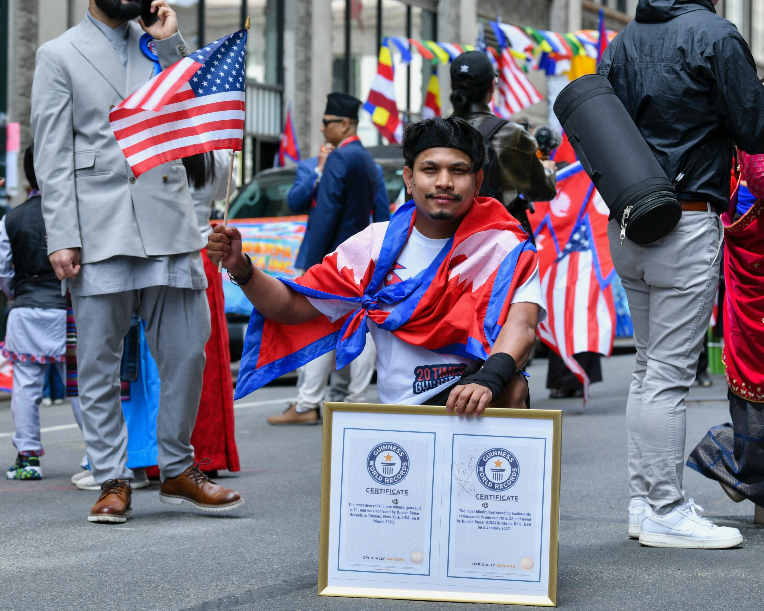 Young man holding a framed certificate at a parade with American flags and people in the background.