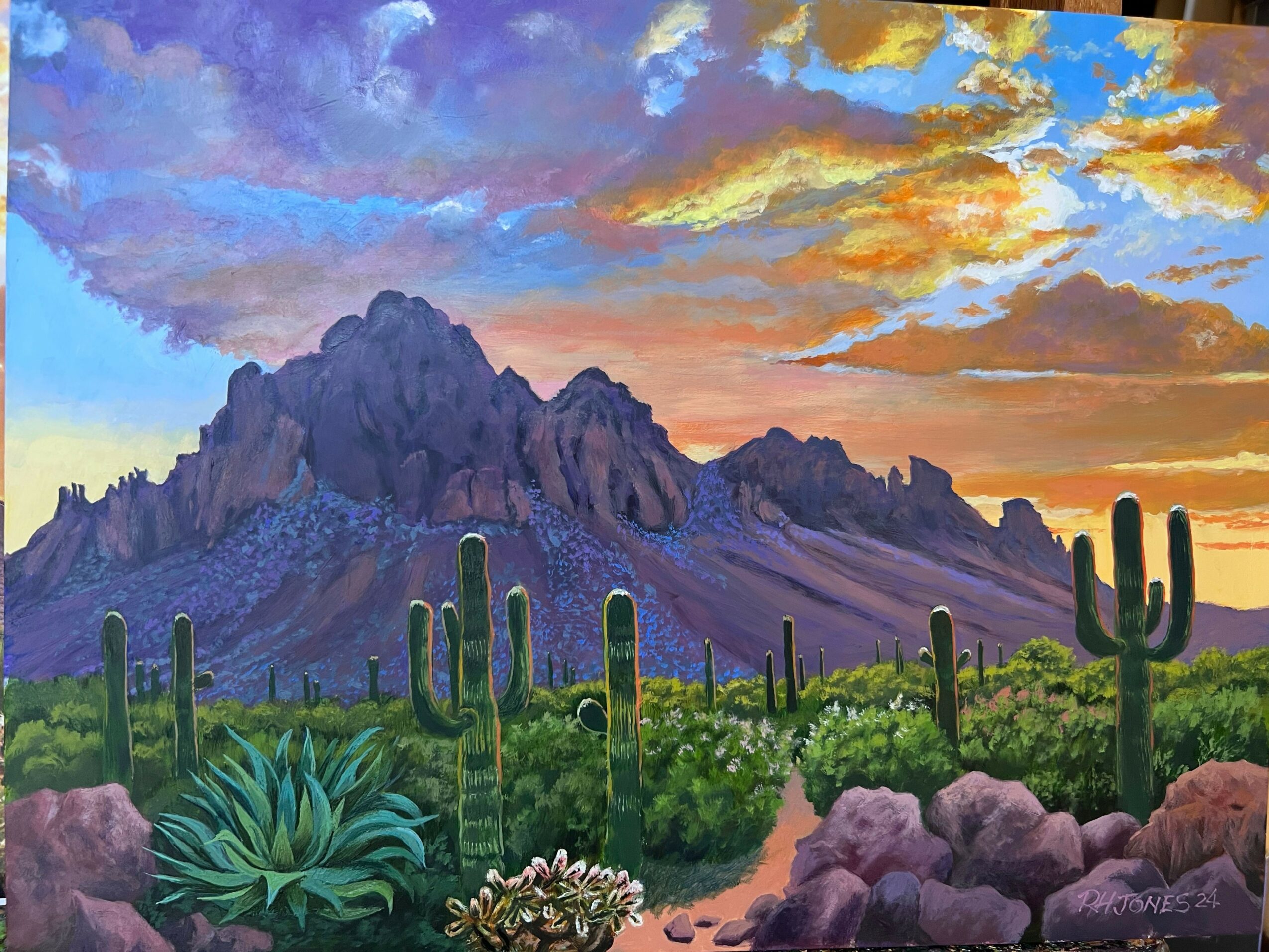 Upside-down landscape painting with mountains, trees, and colorful sky, including clouds and sunset hues.