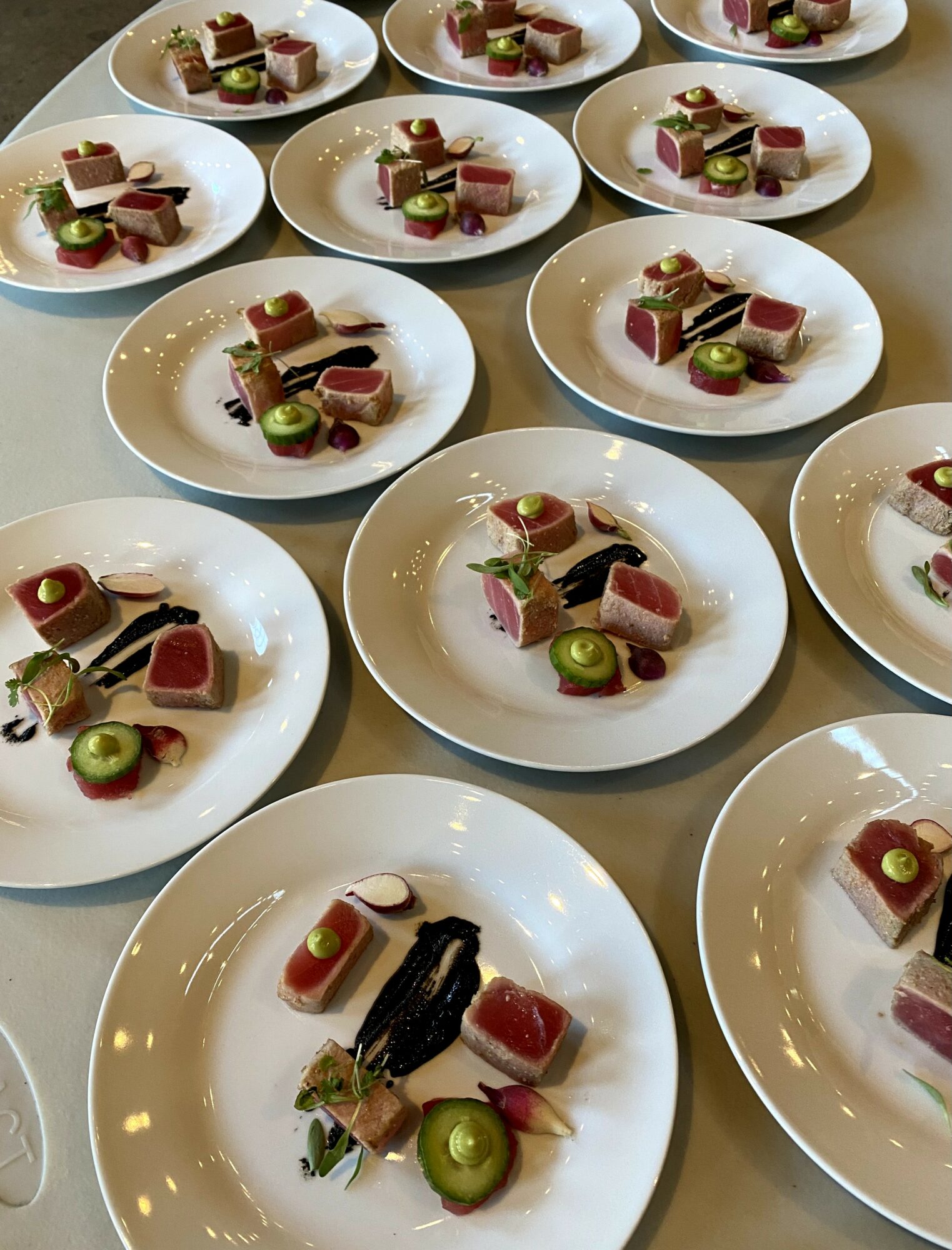 Multiple white plates with assorted desserts and fruit, arranged on a table, viewed from above.