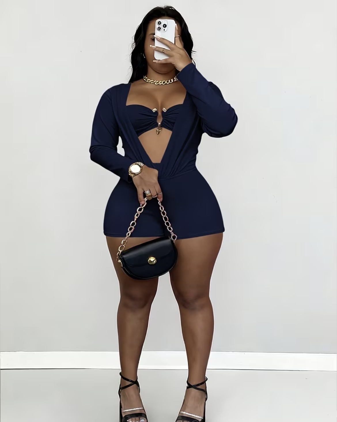 Person taking a mirror selfie wearing a navy blue dress with a sheer cutout, black high heels, and holding a small black purse.