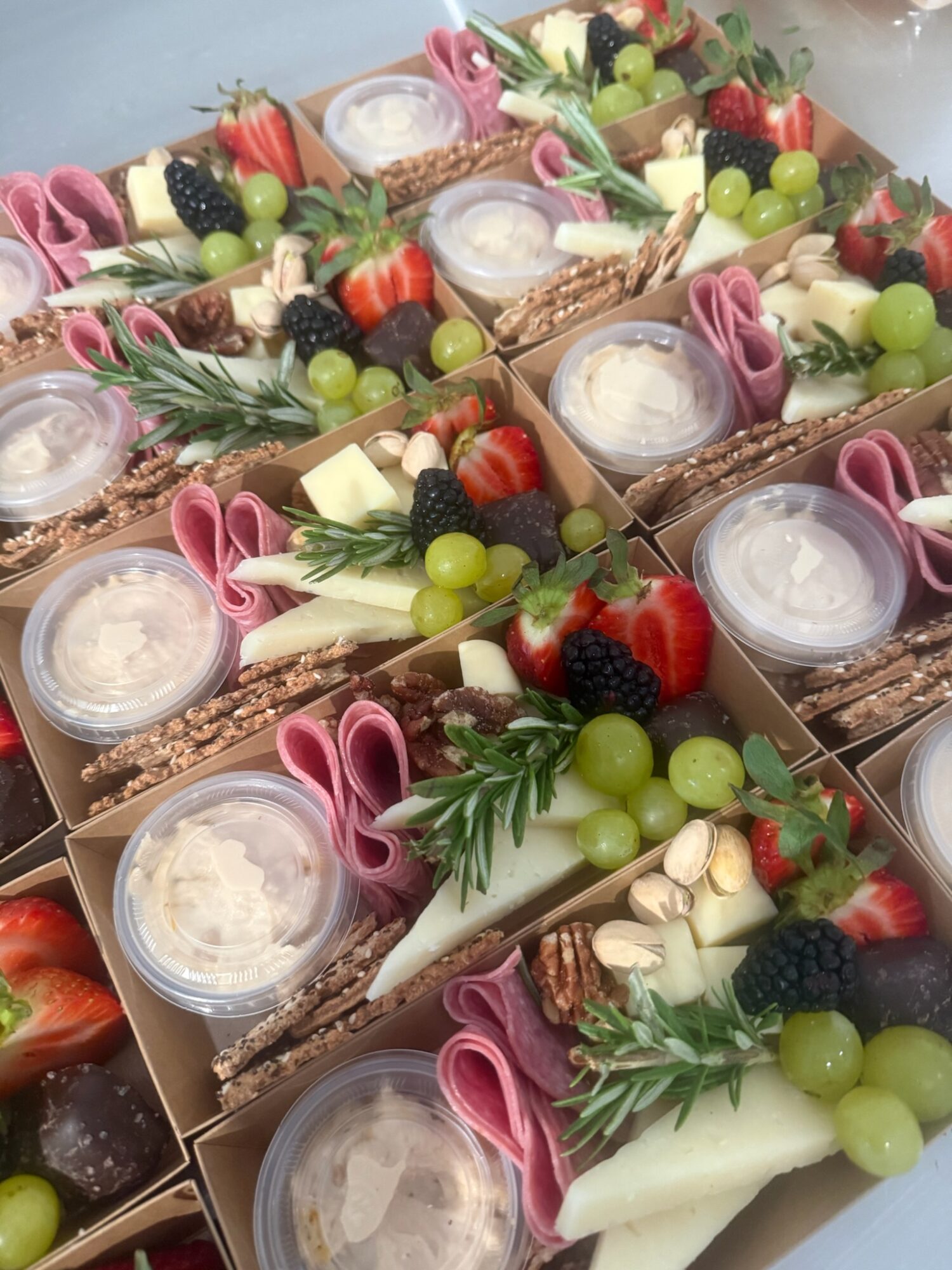 Assorted decorated desserts with fruits, cream, and garnishes arranged in small boxes.