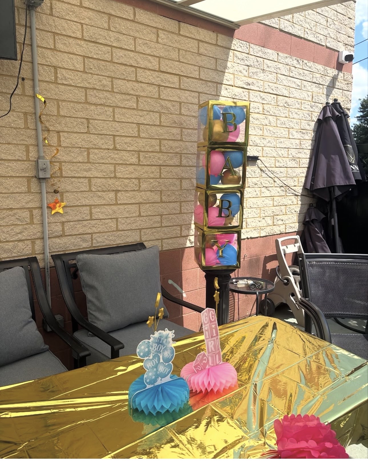 Outdoor patio with table, chairs, and a colorful vertical storage unit against a brick wall.