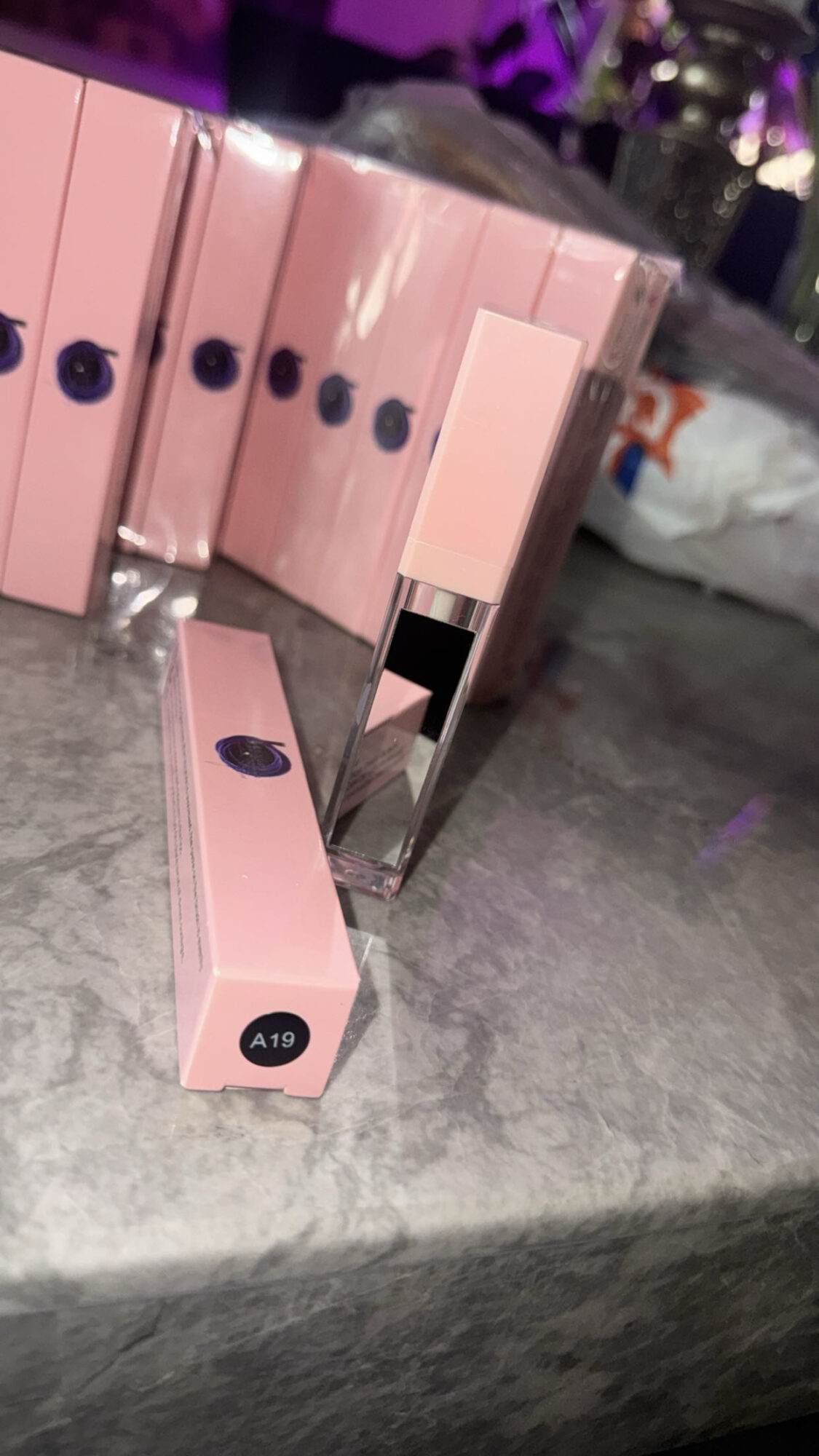 Pink rectangular boxes with black circular labels on a gray surface, some boxes are stacked vertically, one lying flat.