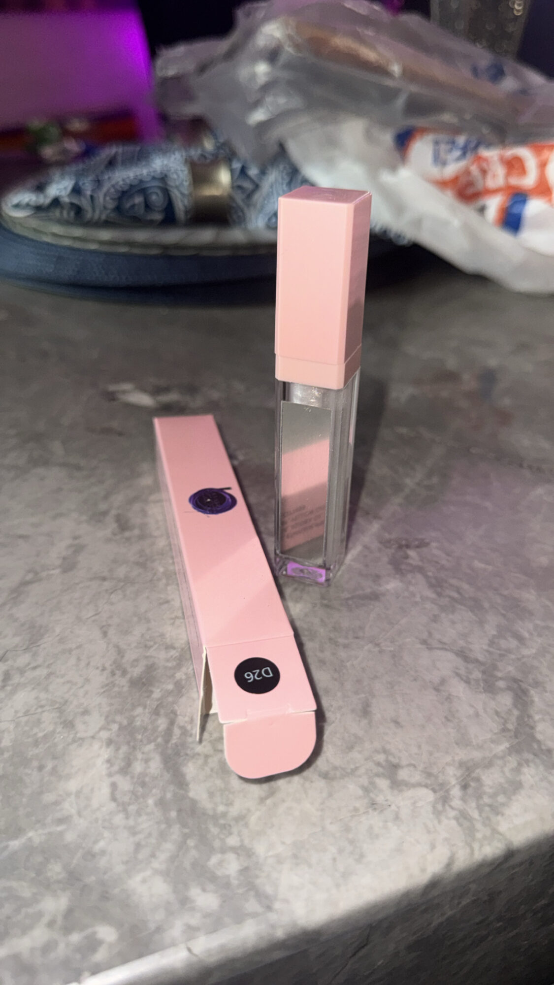 Two pink and clear rectangular objects on a gray surface, with a plastic bag and other items in the background.