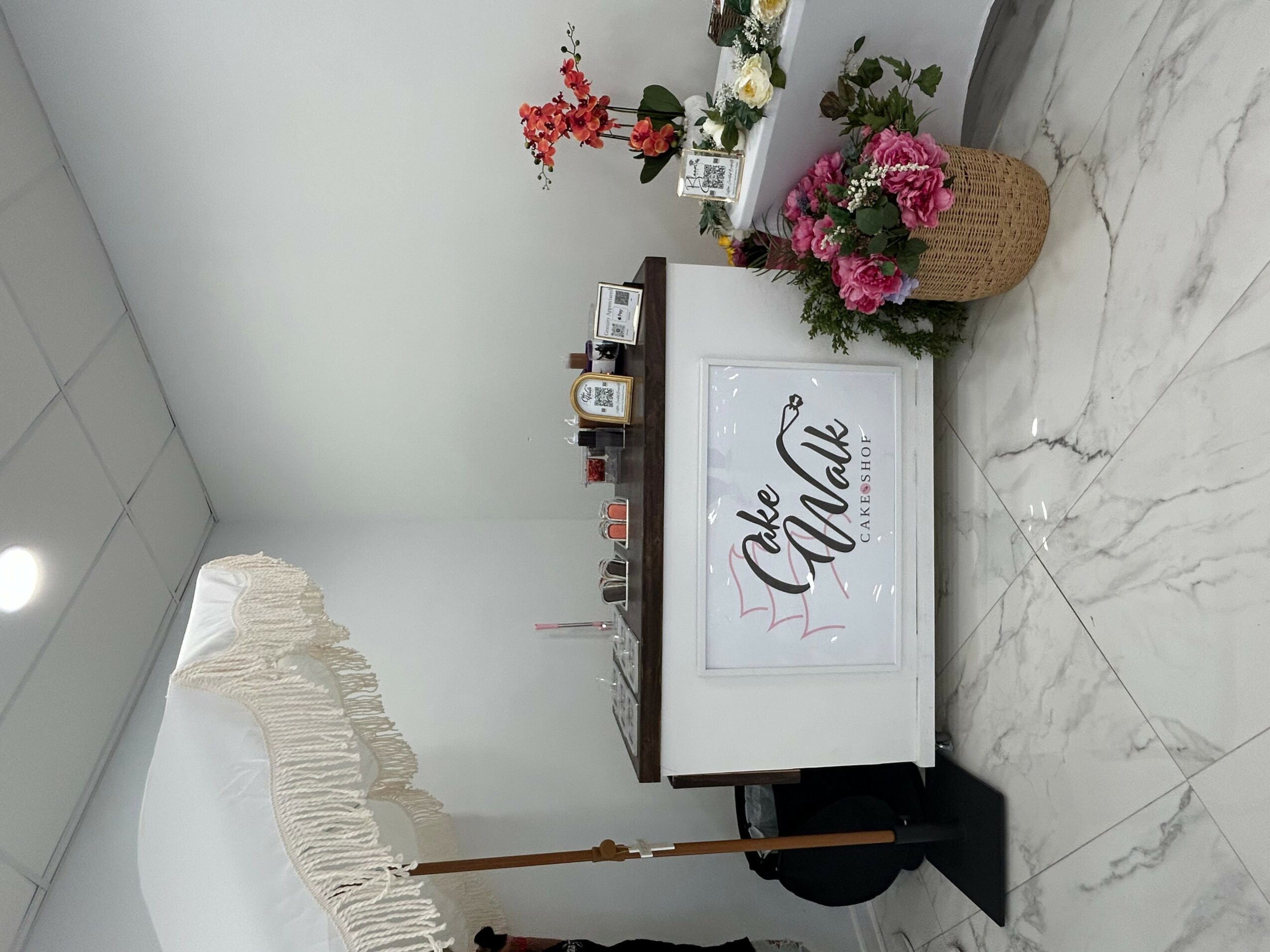Display counter with flowers and products, white sign with 'The Chalk' text, marble floor, and white wall.