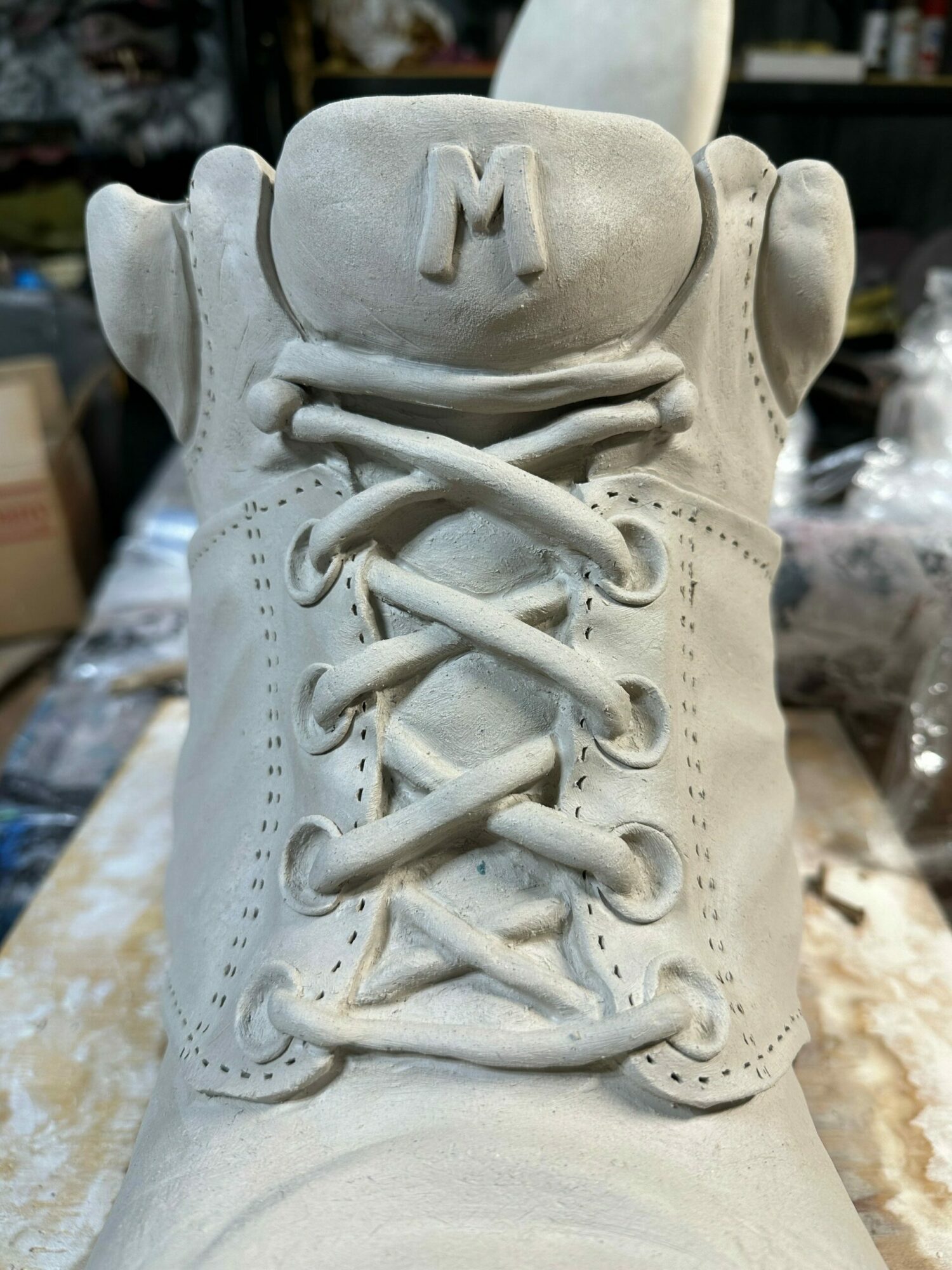 Close-up of a white sneaker with laces and a logo on the tongue, placed on a surface.