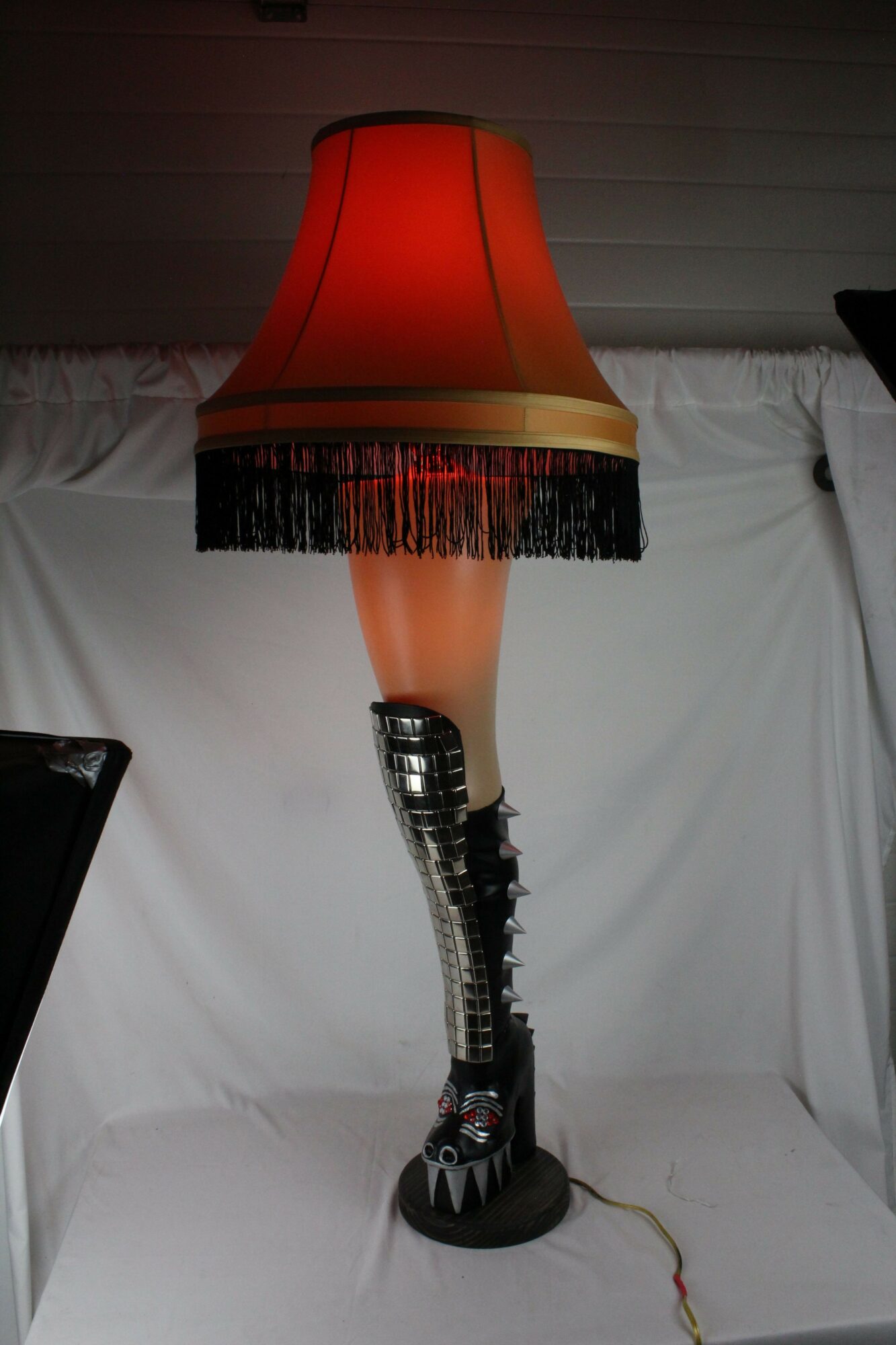 A lava lamp with orange and black colors on a white surface, with a black cord plugged into a wall. Word count: 20