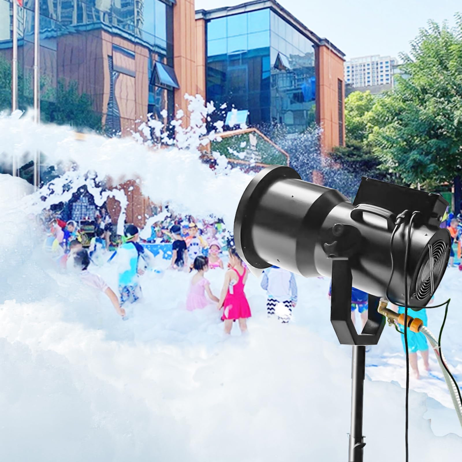 People playing in a foam spray outside modern glass buildings with trees in the background.