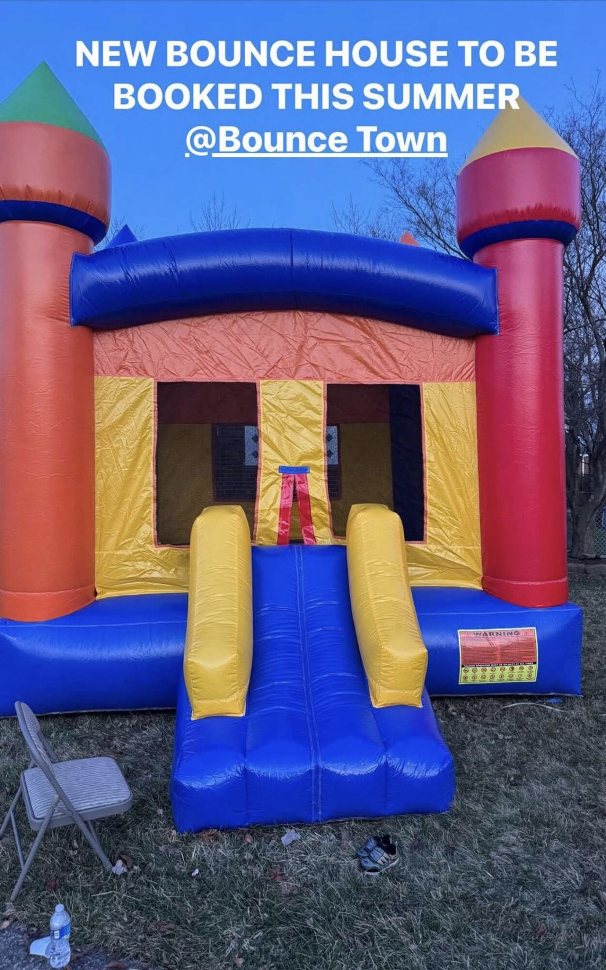 Colorful inflatable bounce house with yellow slides, red and blue towers, and a blue arch, outdoors on grass.