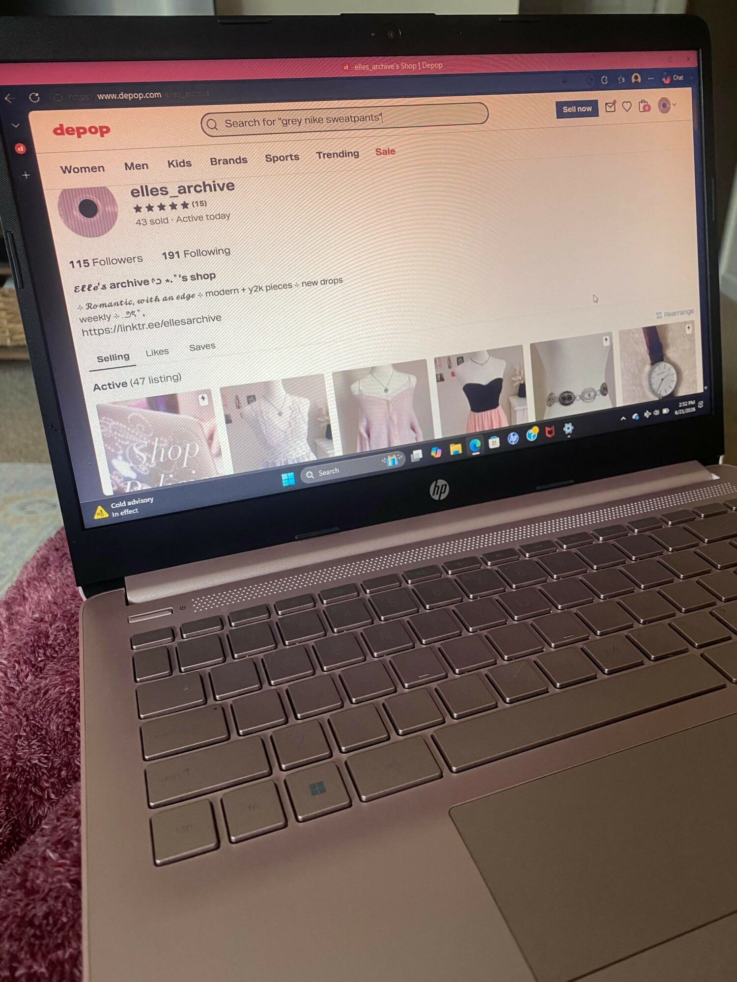 Laptop screen displaying a webpage with search results and images, keyboard visible, person wearing pink clothing nearby.
