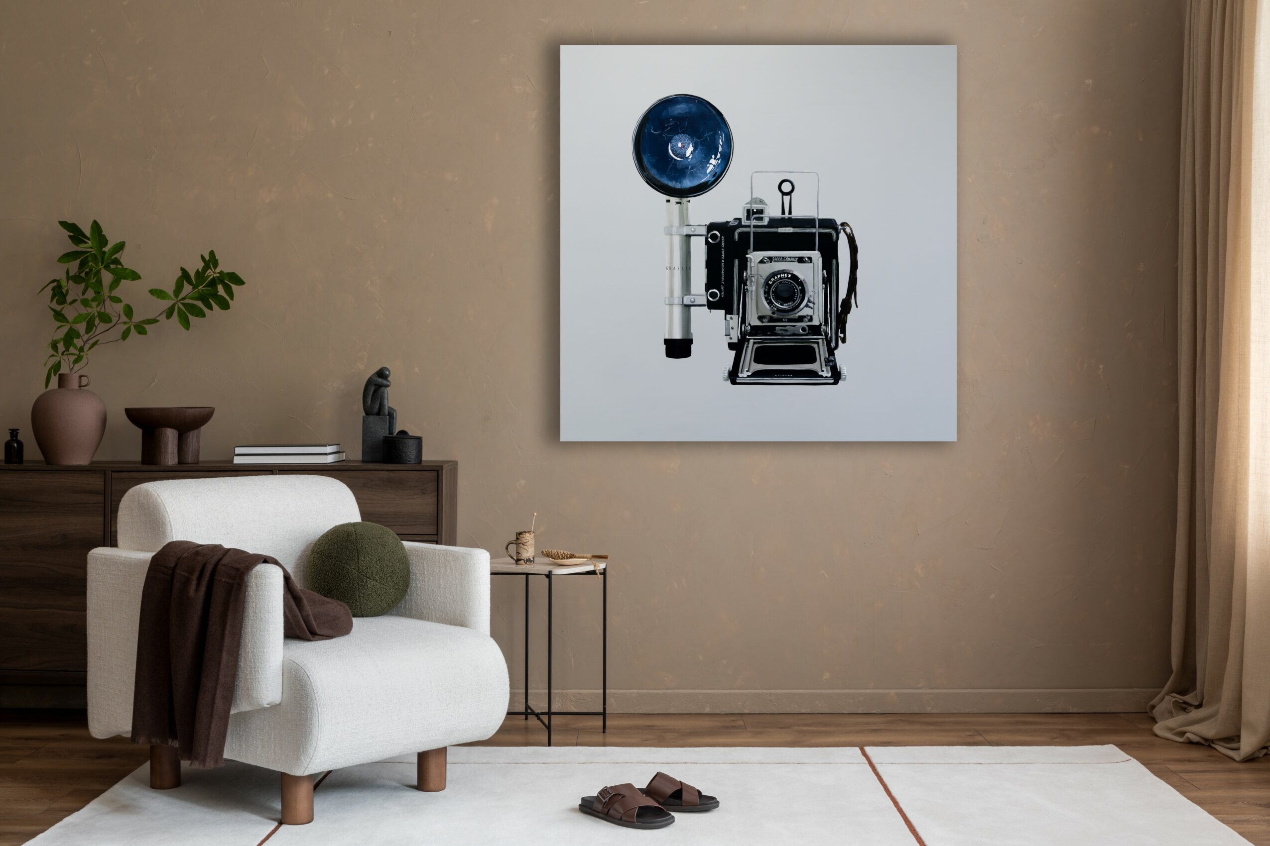Living room with a white sofa, side table, wall art of a camera, and a potted plant, beige walls, and curtains.