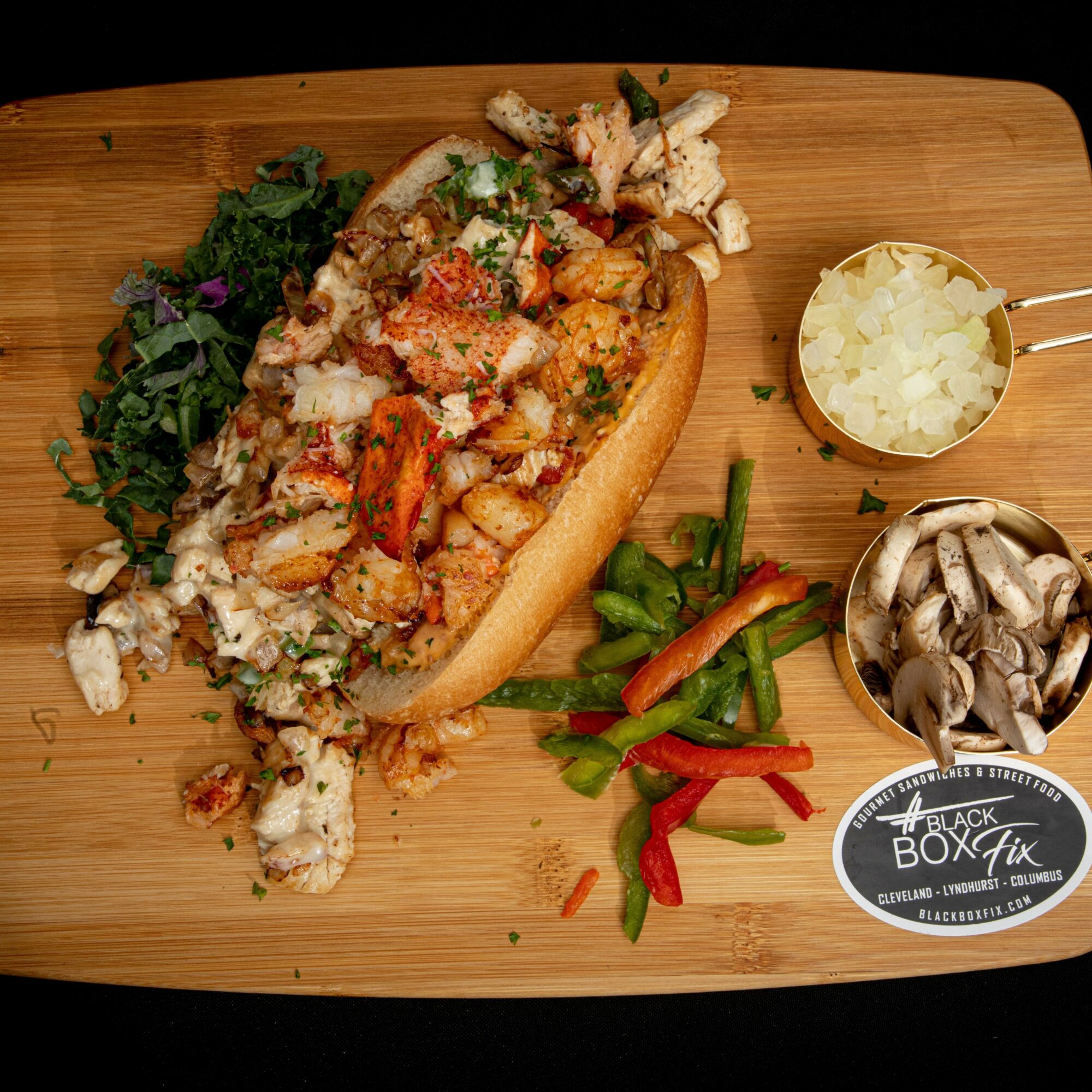 Lobster roll with lettuce, chopped onions, and vegetables on a wooden board, with side mushrooms and onions, and a logo sticker.