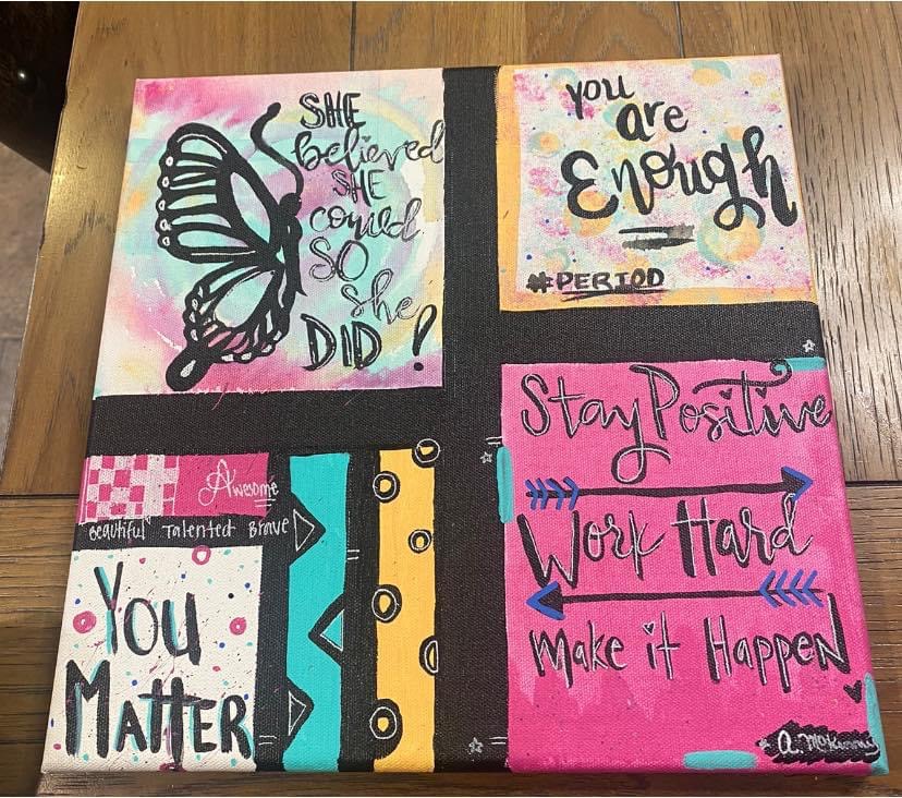 Four colorful motivational posters with handwritten messages and designs on a wooden surface.