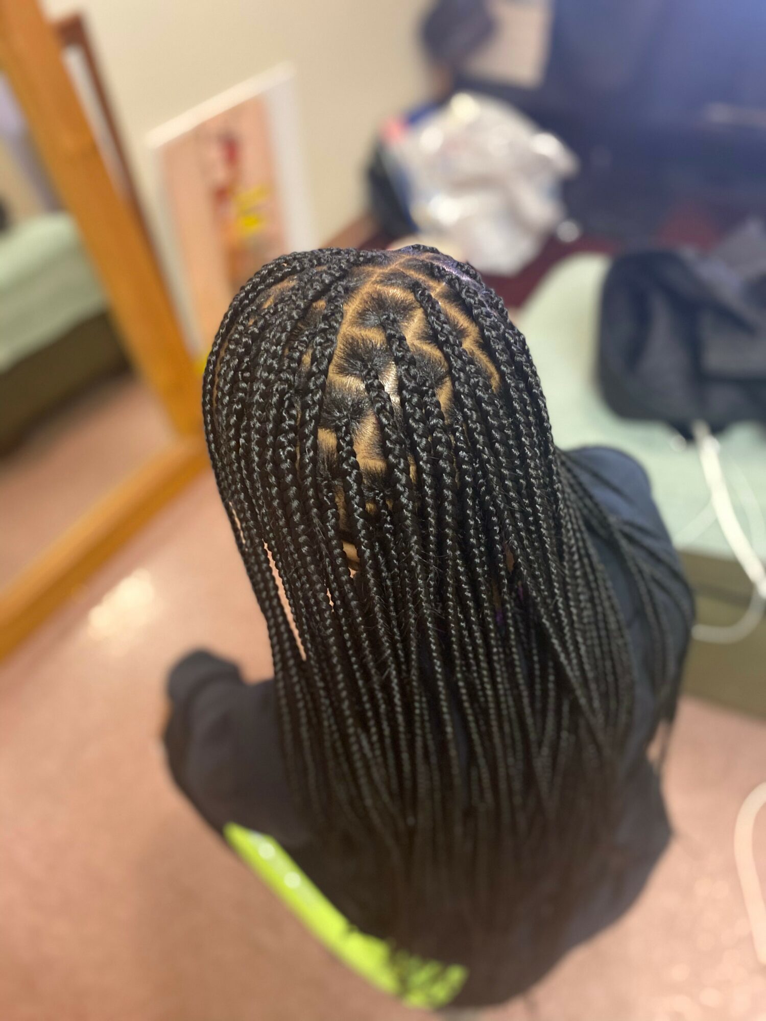 Top view of a person with braided hairstyle, showing neat, small braids arranged in a pattern on the scalp.