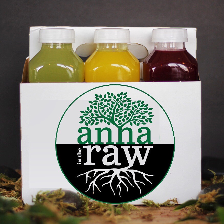 Three bottles of juice in a white box, with a logo featuring a tree and roots, on a dark background.
