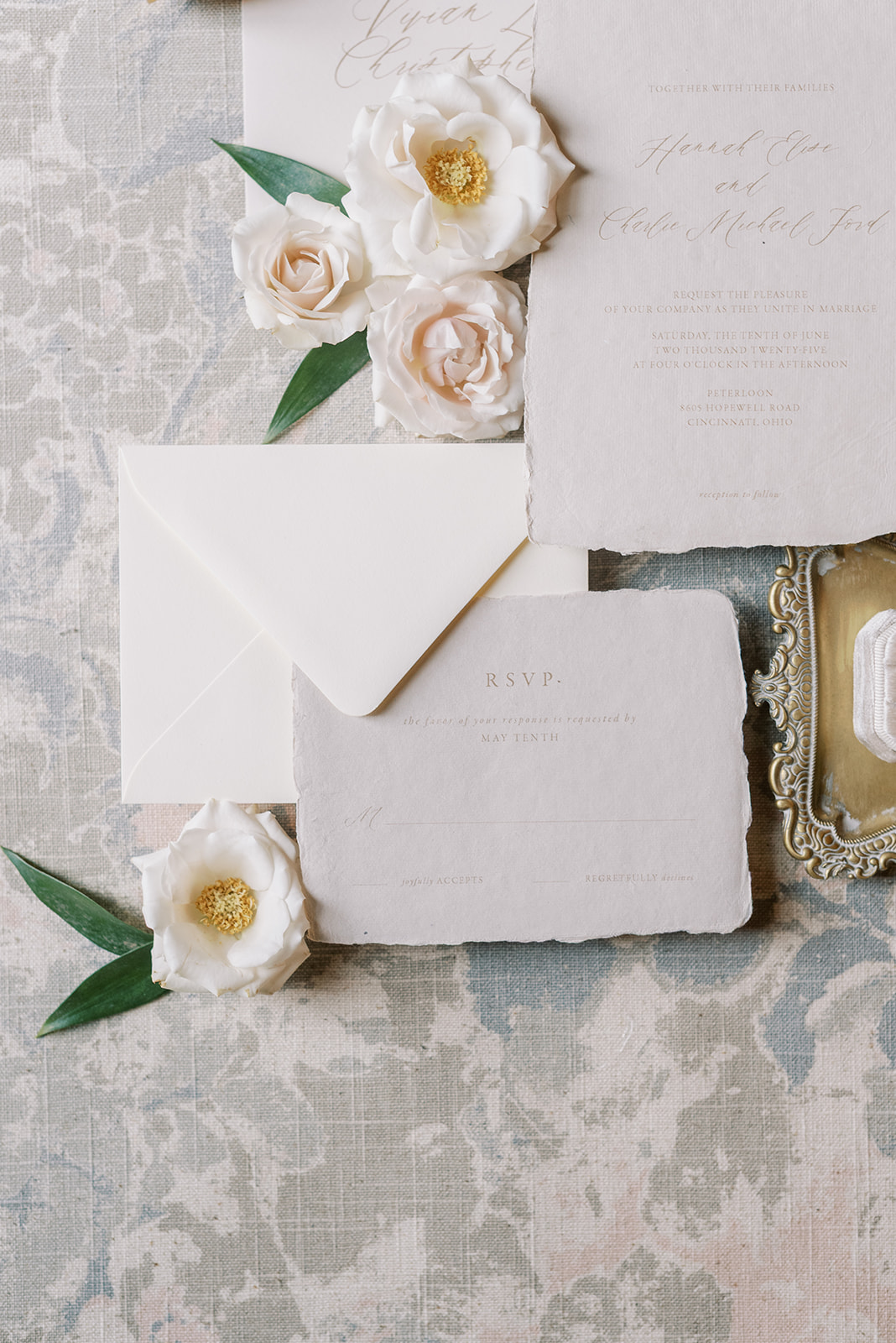 Flat lay of white flowers, a white envelope, and handwritten notes on lace fabric background.