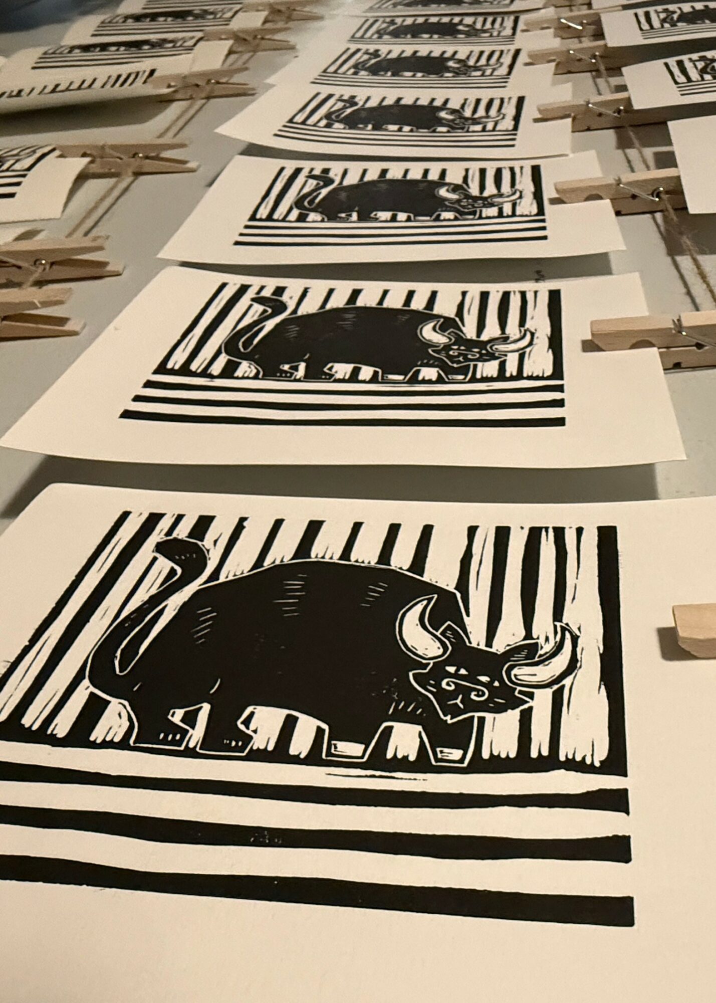 Black and white print of a stylized animal, possibly a pig, with bold stripes in the background and foreground.