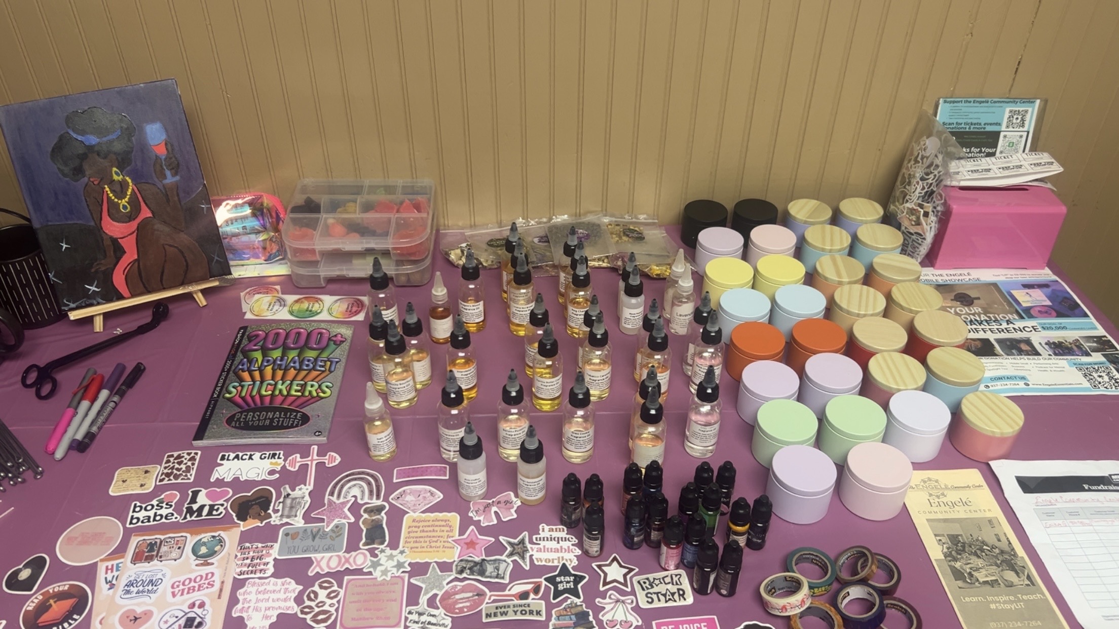 Table with colorful nail polish bottles, stickers, and beauty supplies, against a yellow wall background.