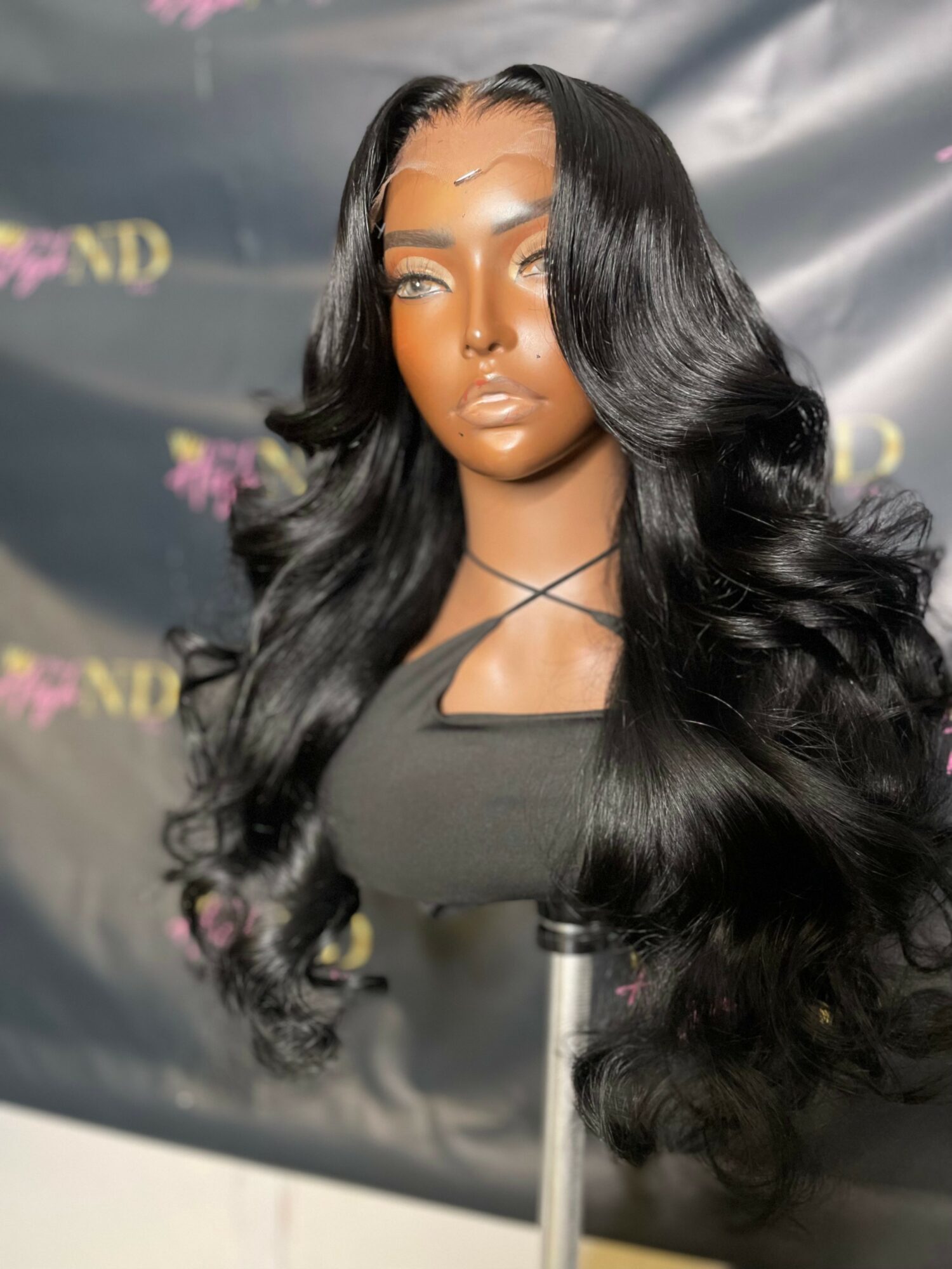 Bust of a woman with long, wavy black hair and makeup, against a dark background with purple and yellow text.