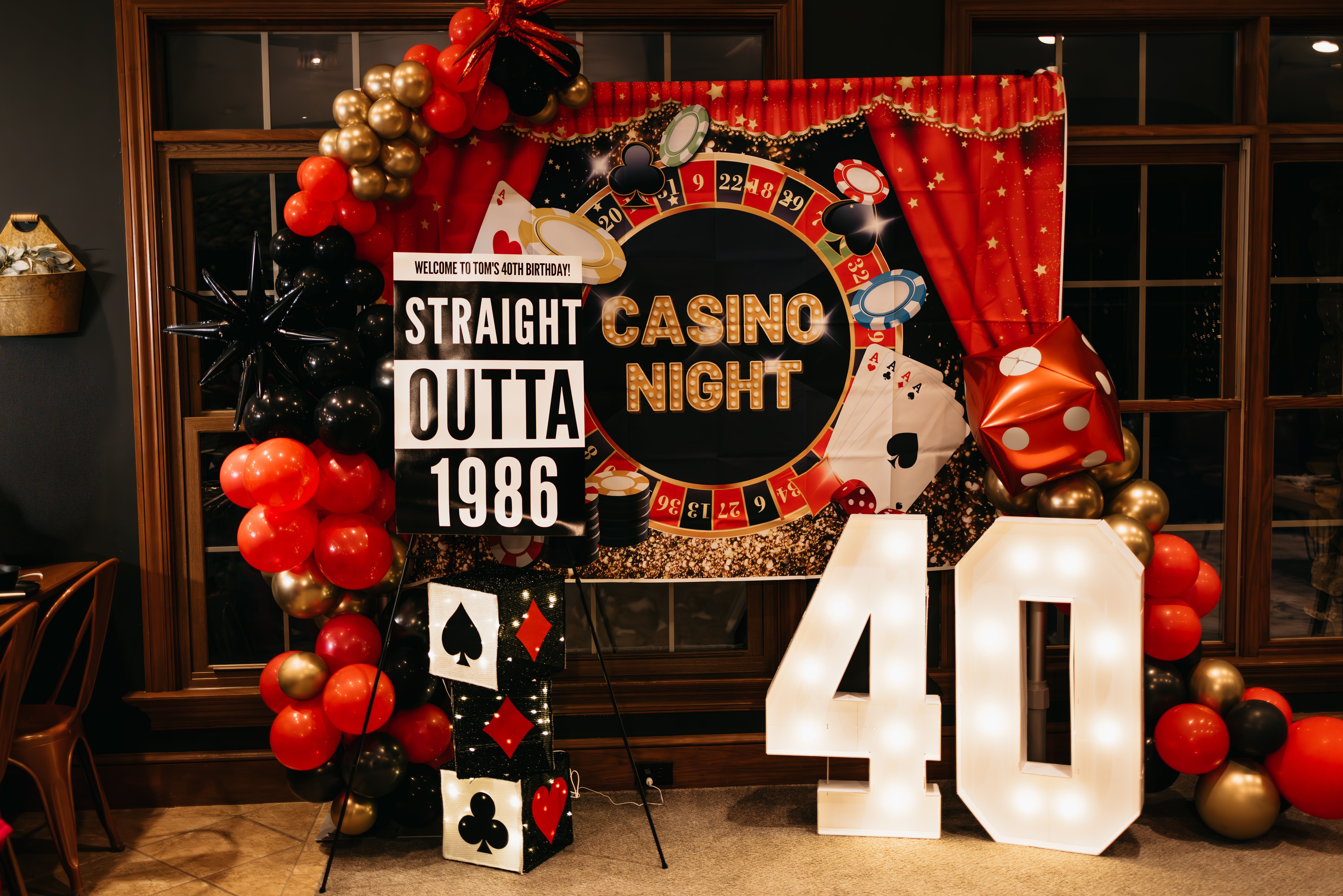 Decorative casino-themed backdrop with balloons and large number 40 for a celebration, featuring poker chips and playing cards.