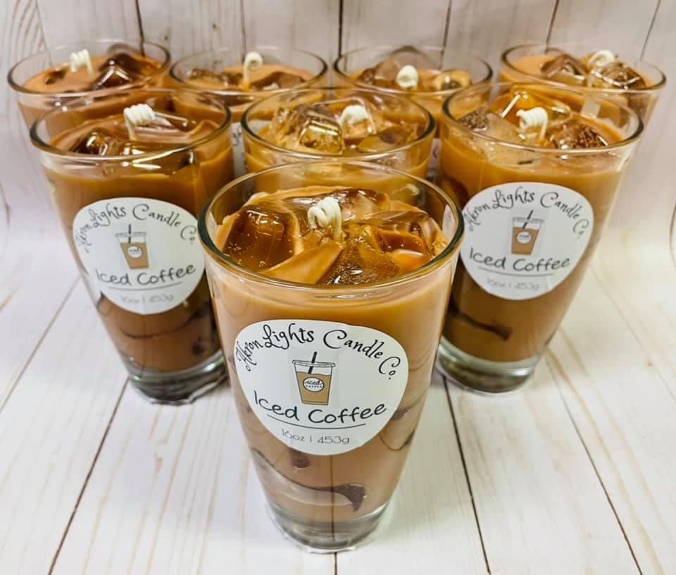 Seven glasses filled with iced coffee topped with marshmallows, labeled 'Lights Candle Iced Coffee,' on a white surface.