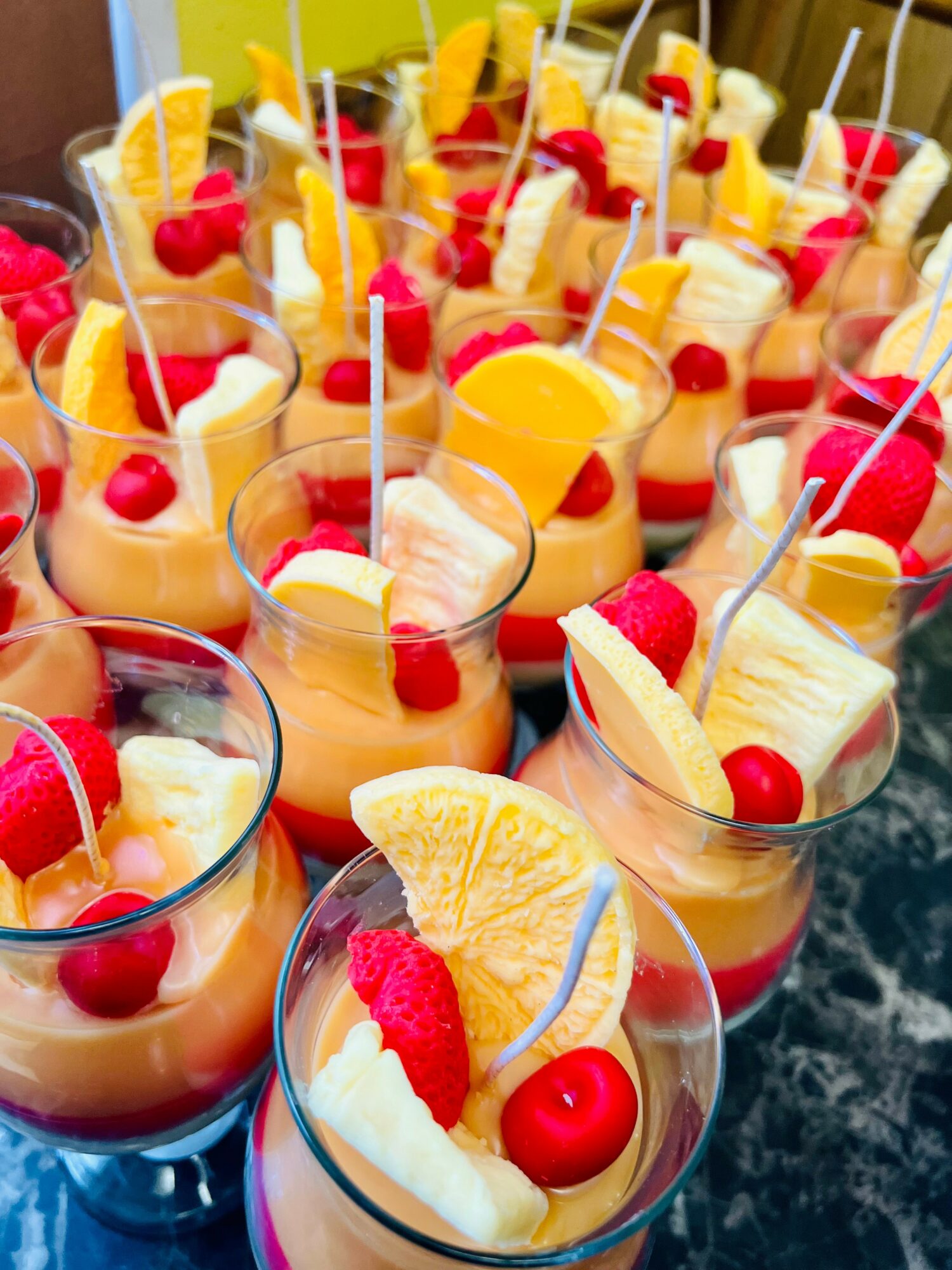 Multiple tropical drinks with pineapple, cherry, and whipped cream garnishes on a dark surface.