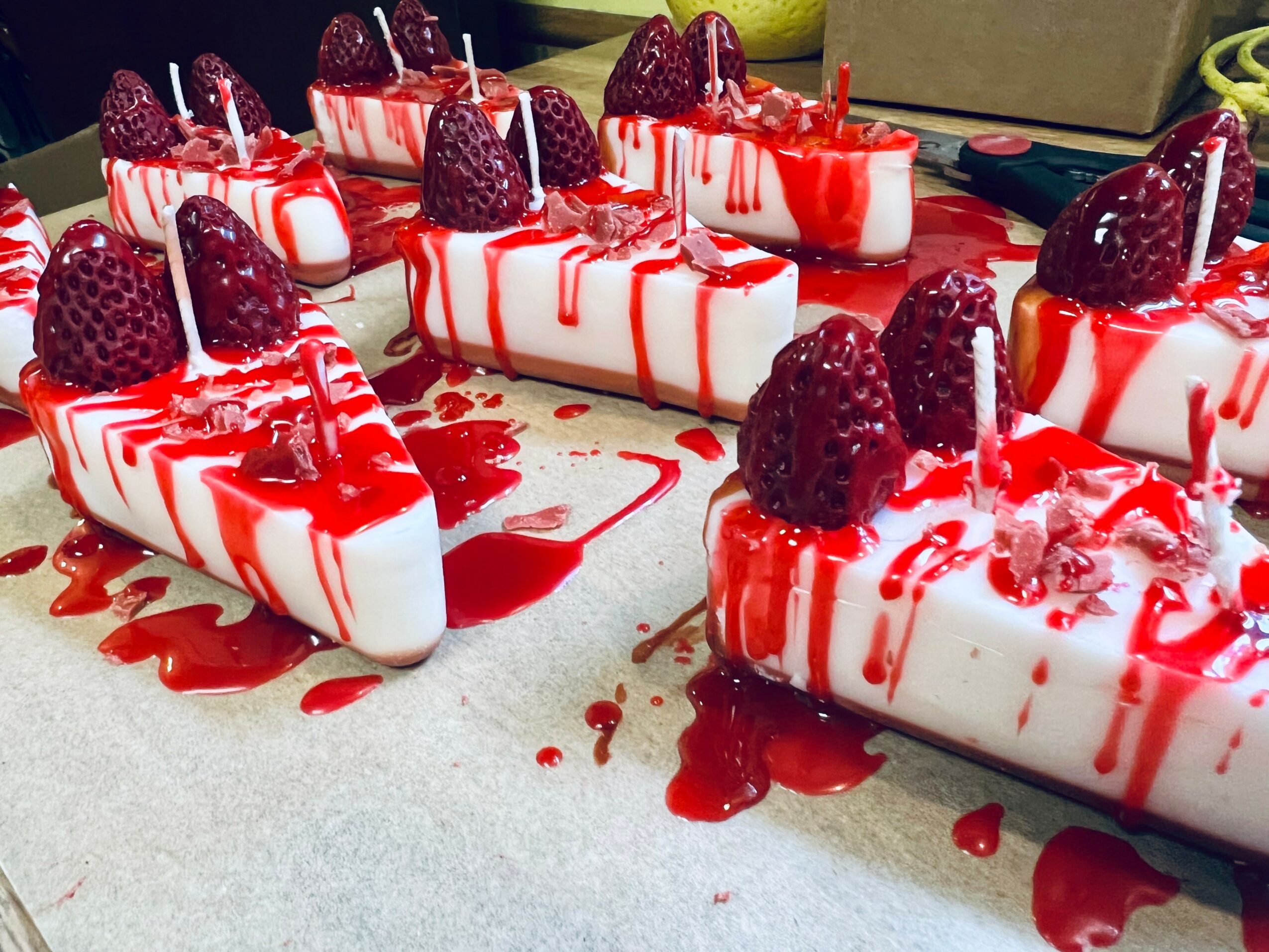 Several slices of cheesecake topped with raspberries and drizzled with red sauce on a white surface.