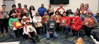 Group of people, some holding wrapped gifts, gathered indoors for a celebration or event.