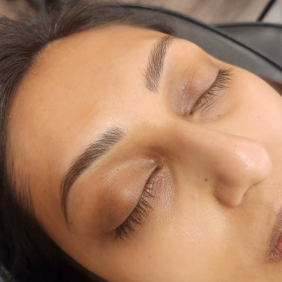 Close-up of a woman's face with closed eyes, showing well-groomed eyebrows and long eyelashes.