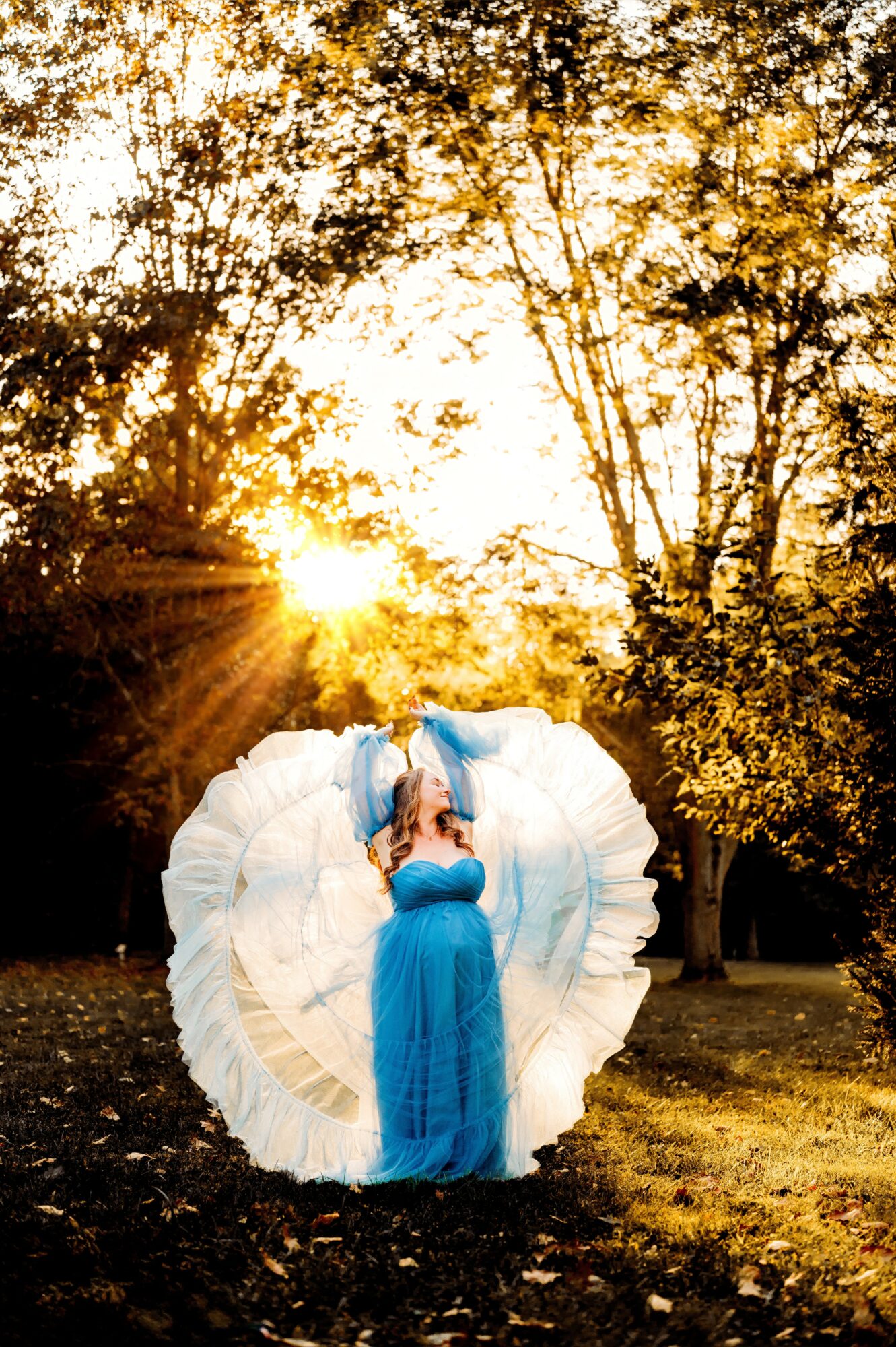Person in a blue dress standing outdoors with trees and sunlight, holding a large white heart-shaped object.