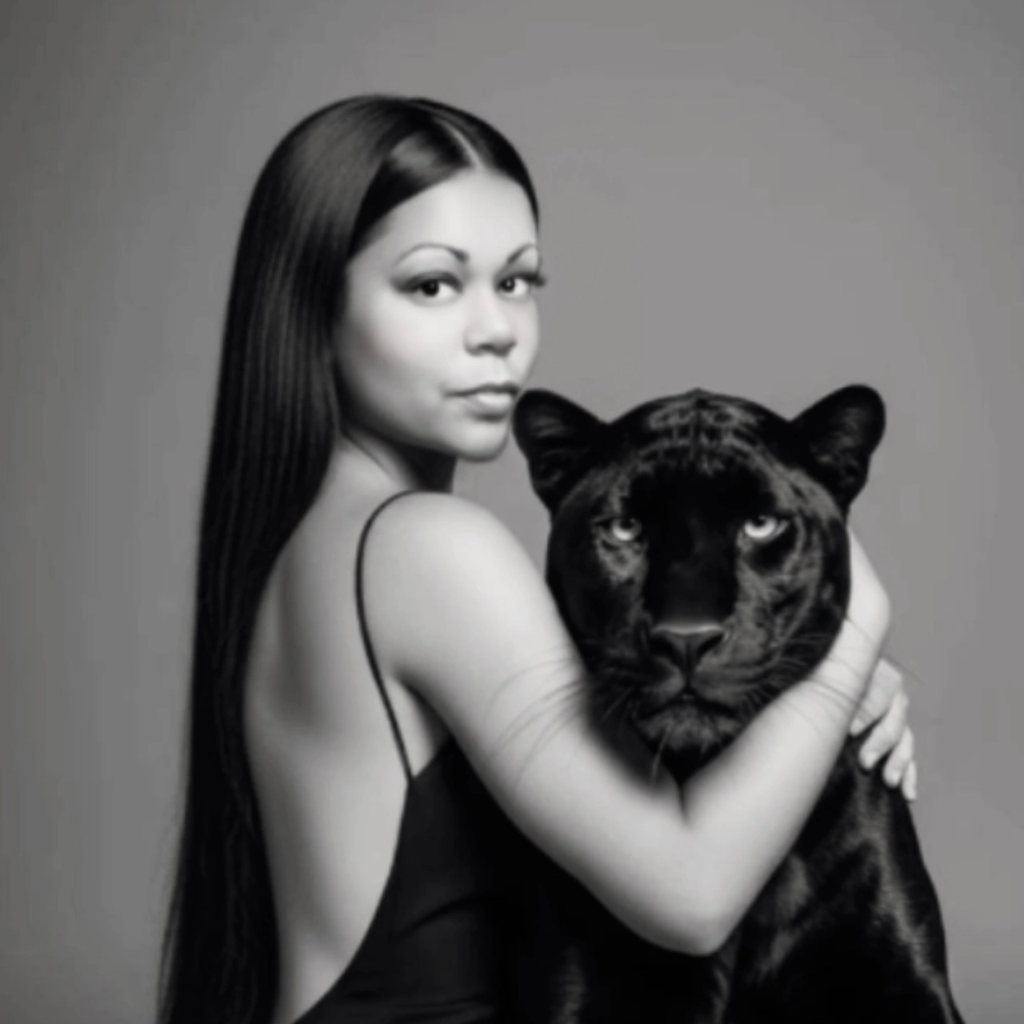 Woman with long hair holding a large black panther, both facing forward, in black and white.