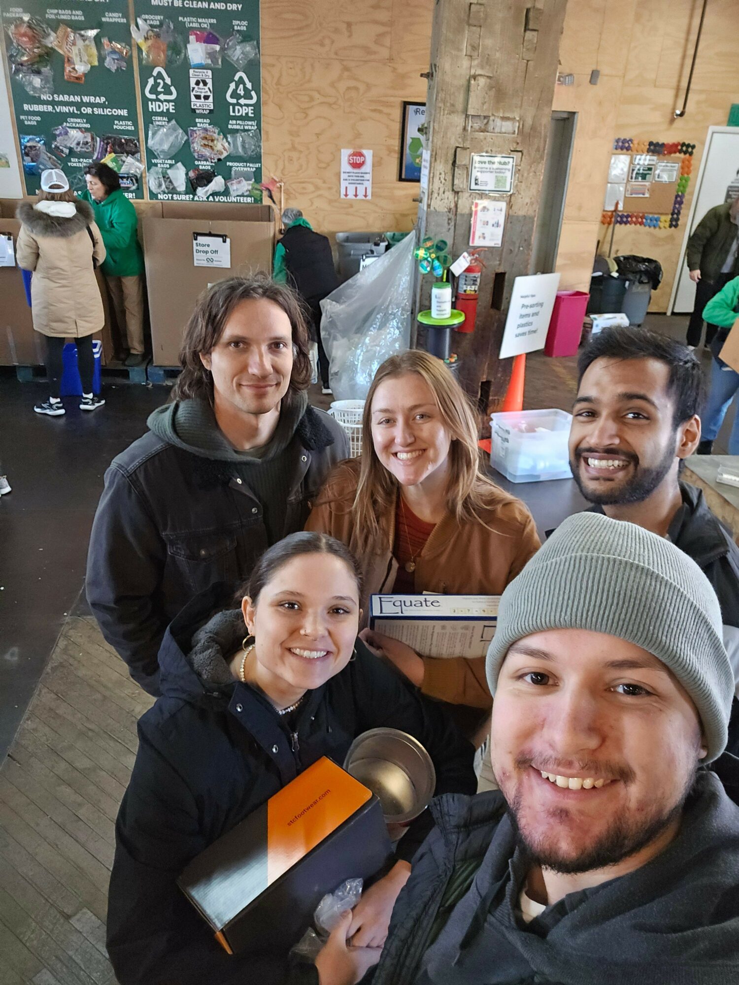 Four people smiling in a store, with shelves and posters in the background.