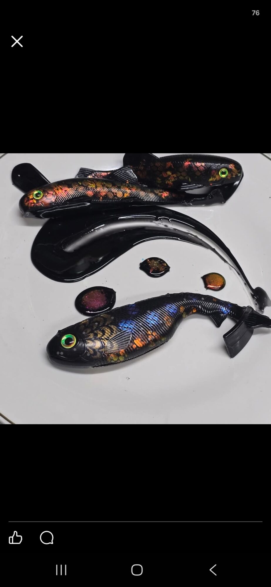 Four colorful fish-shaped objects and a black curved object on a white surface.