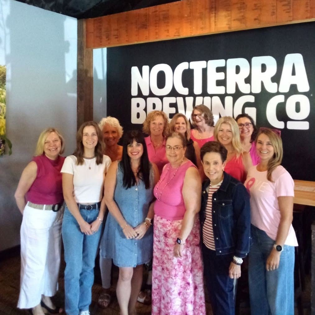 Group of women standing indoors in front of a sign that reads 'NOCTERRA BREWING CO'.