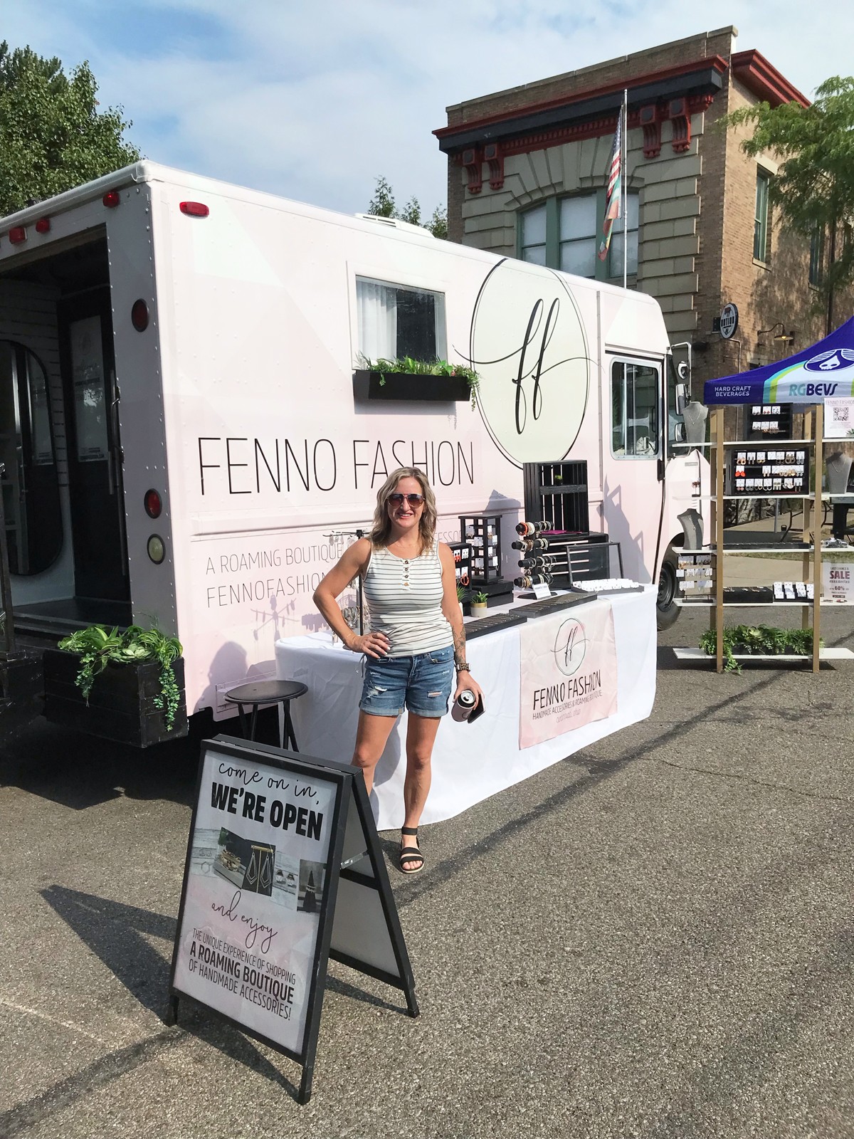 Woman standing in front of a mobile fashion store with signage and outdoor setup.
