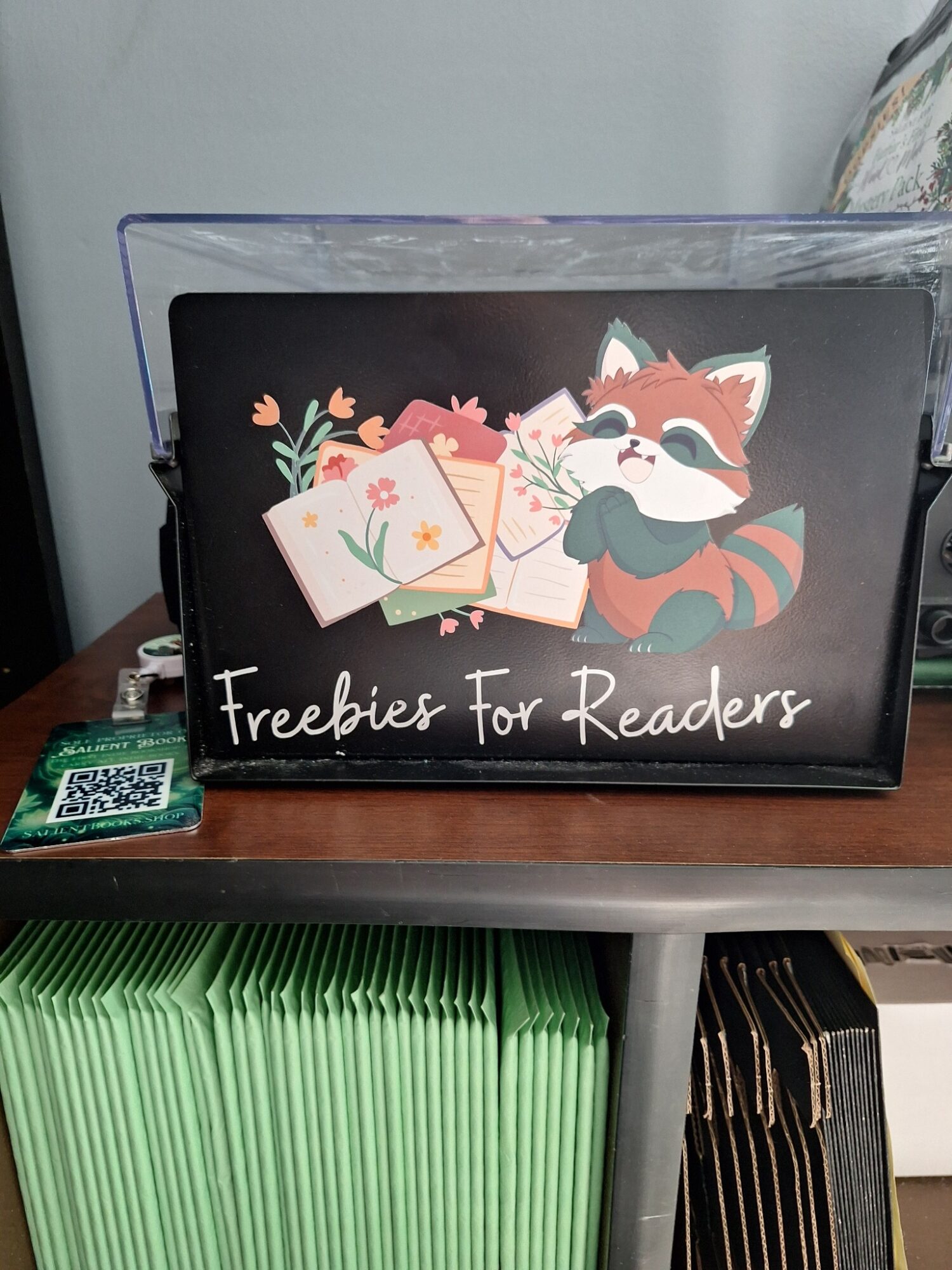 Box with a fox illustration holding envelopes and flowers, labeled 'Freebies for Readers', on a shelf.