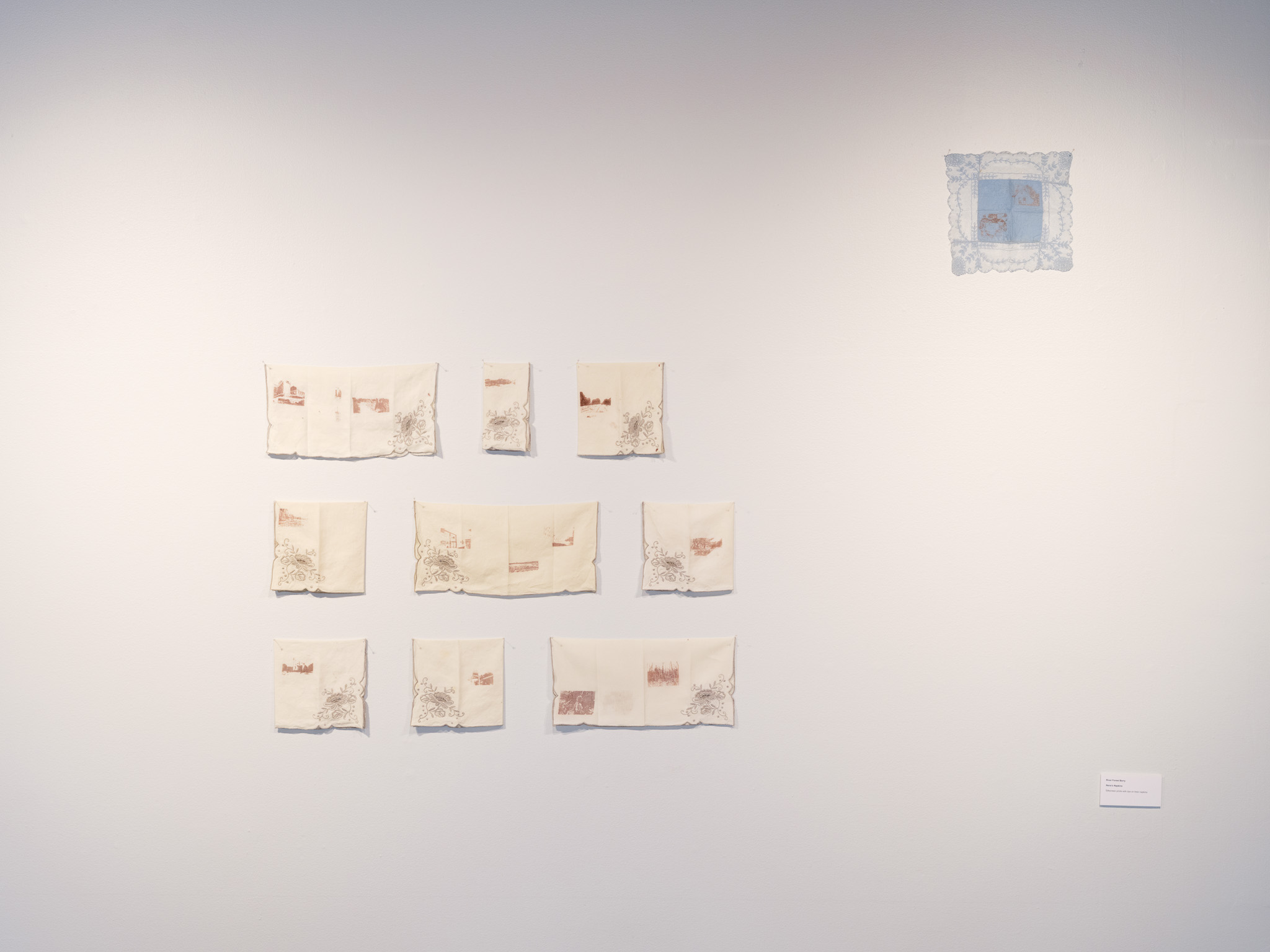 Gallery wall with nine small artworks arranged in a grid pattern, and one larger artwork on the right, all on a white wall.