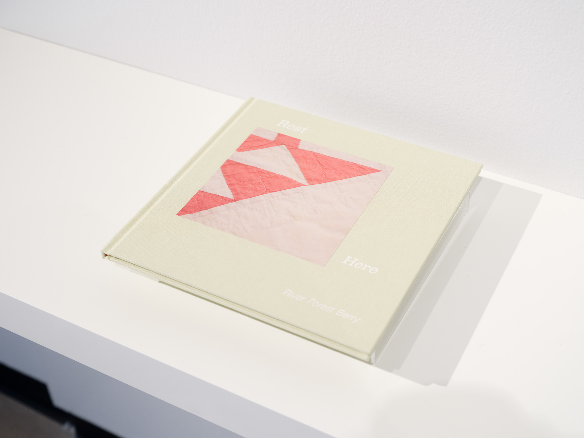 Open book with geometric pink and red shapes on a white background, placed on a white surface.