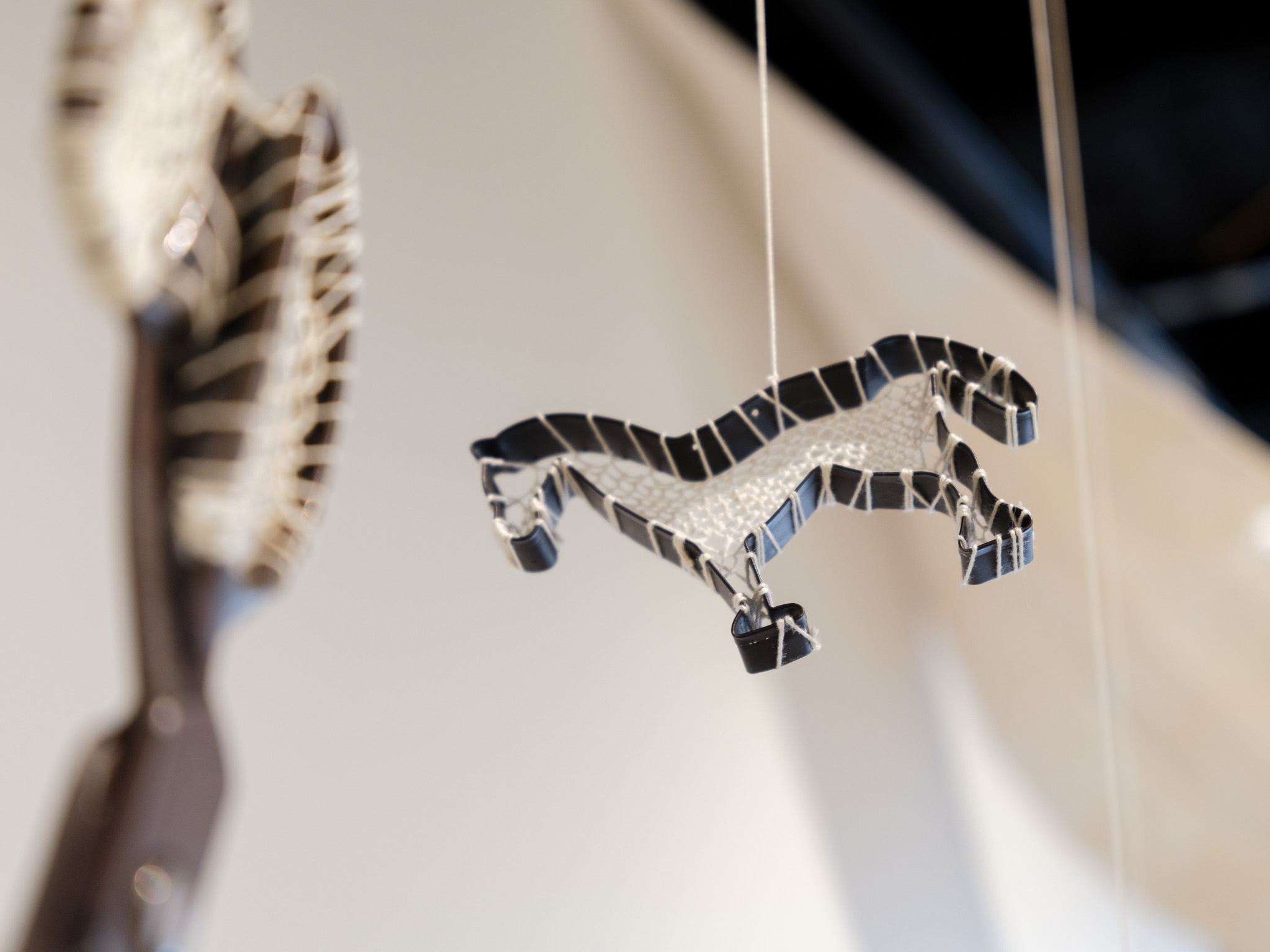 Hanging black and white striped animal-shaped decoration, possibly a lizard or gecko, suspended by a string.