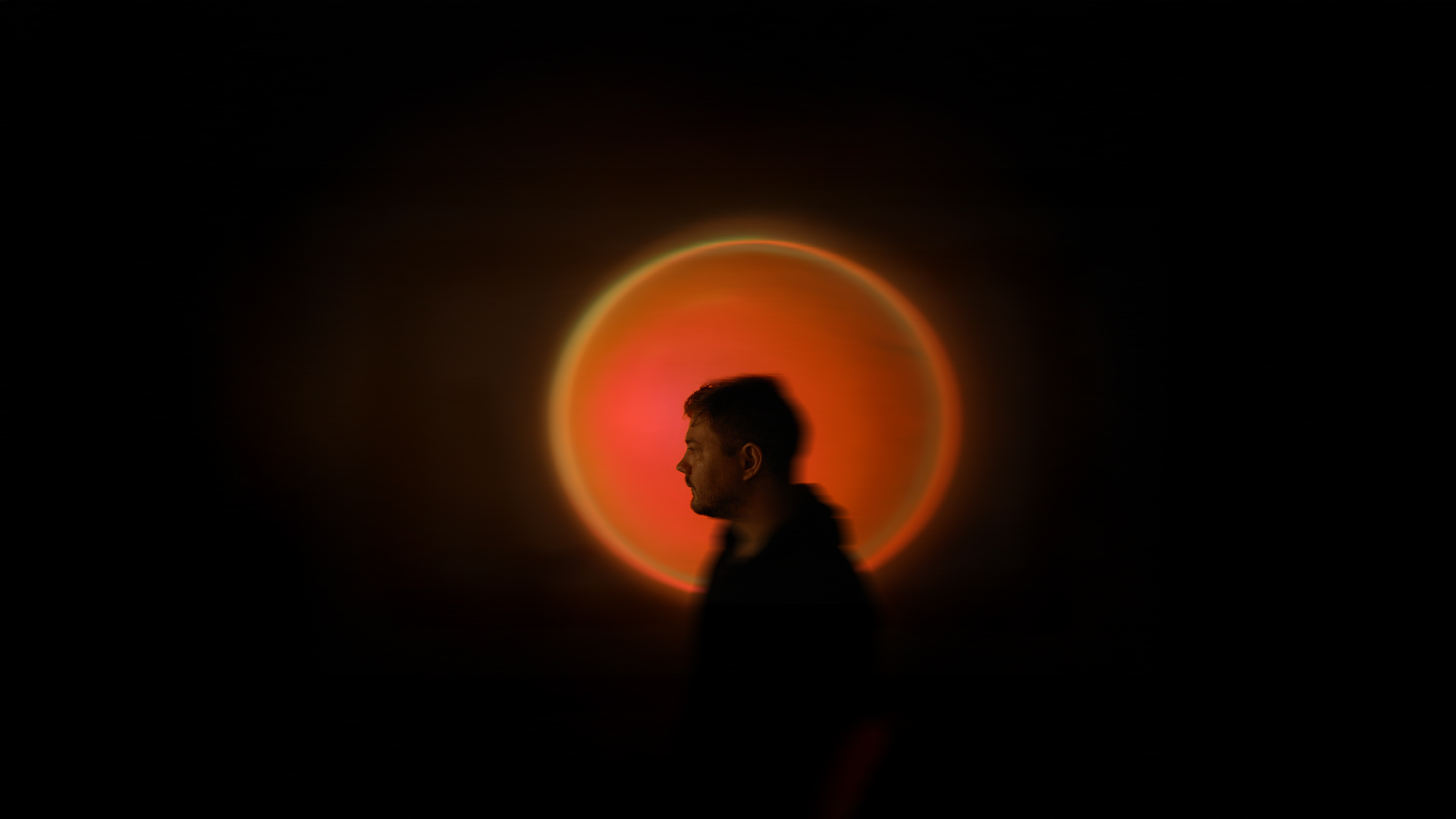 Silhouette of a person in front of a glowing, circular light source resembling a solar eclipse or sunset.