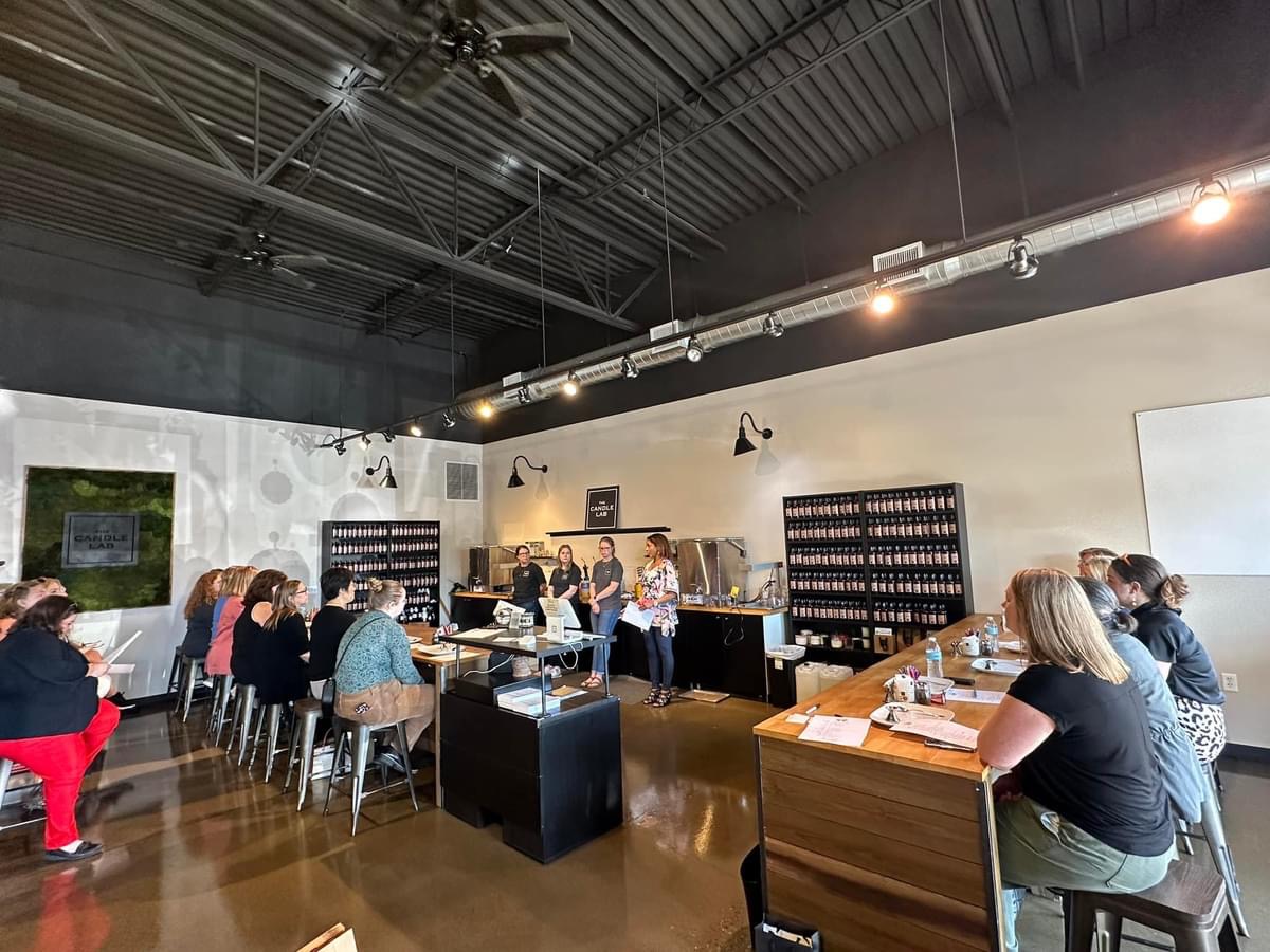 People seated at tables in a modern, industrial-style room with high ceilings and black lighting fixtures.